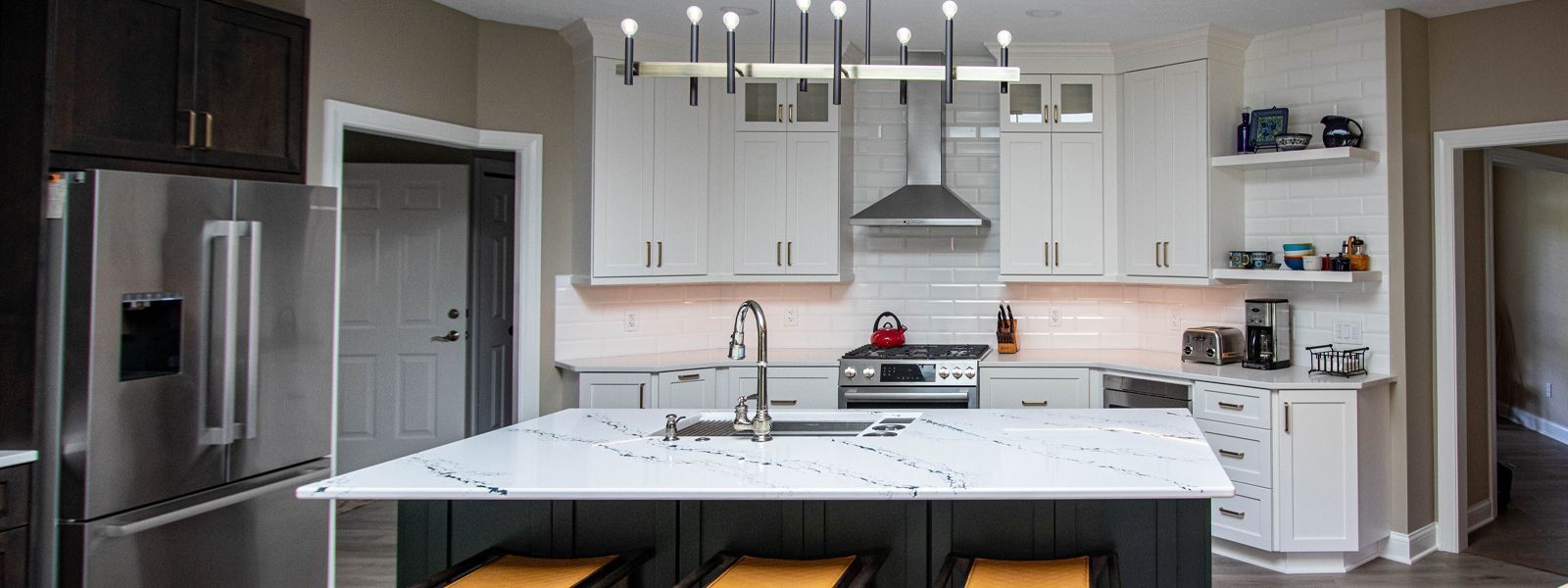 A kitchen with white cabinets , stainless steel appliances , and a large island.