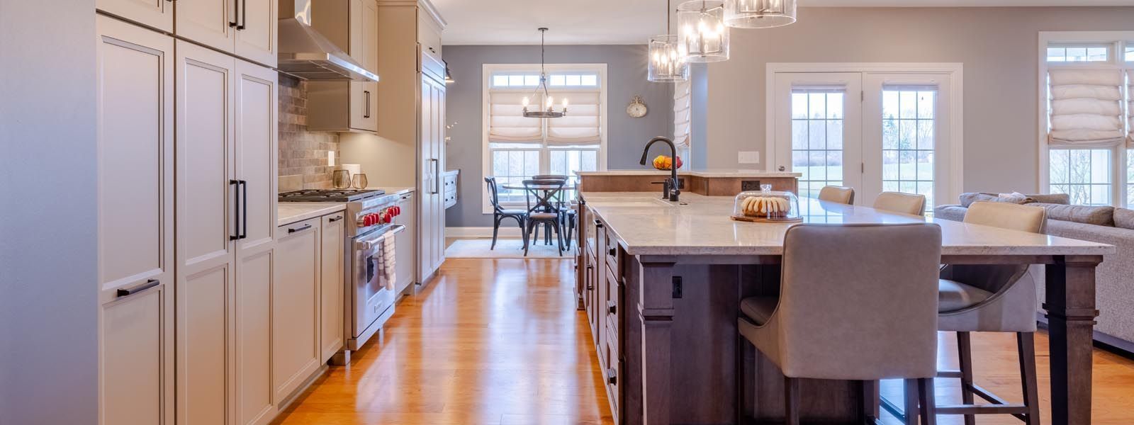 A kitchen with hardwood floors , white cabinets , stainless steel appliances and a large island.