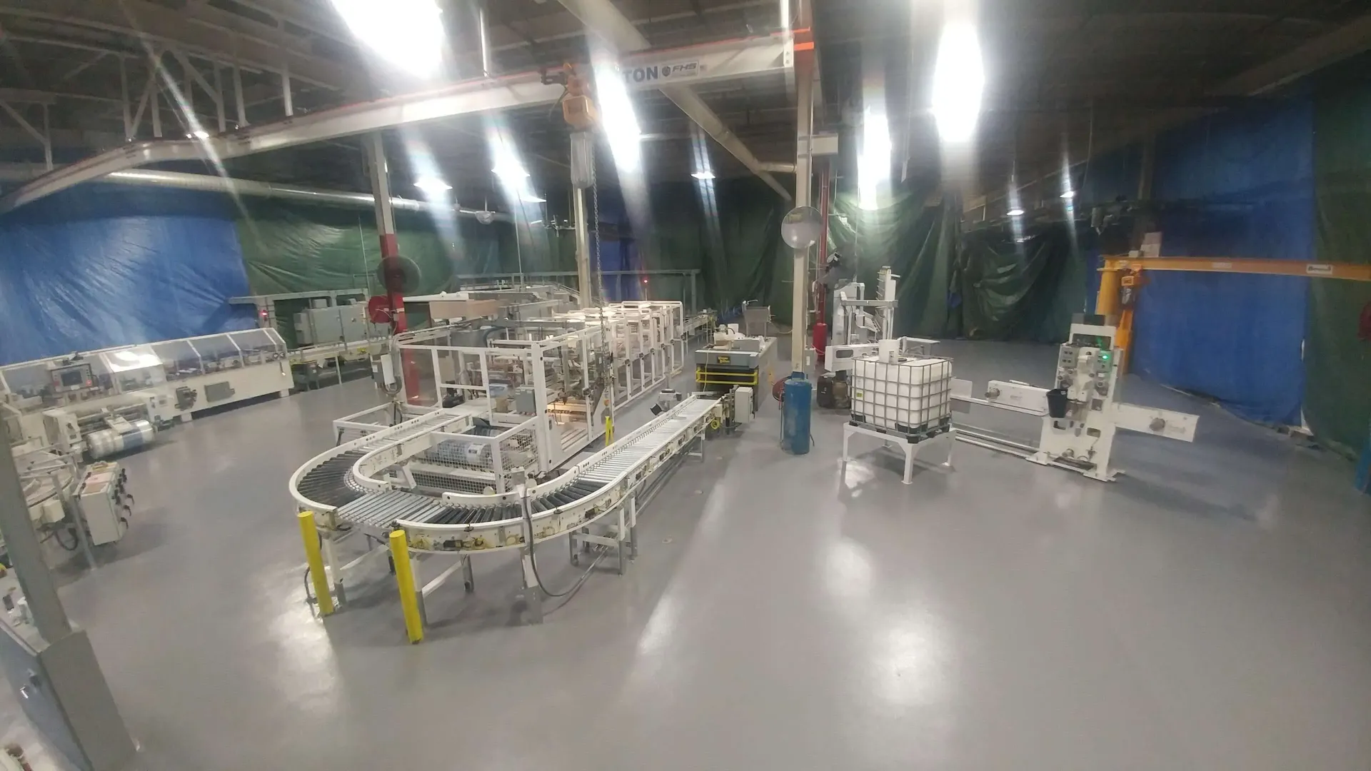 Factory floor with automated machinery and conveyor belts. Grey floor, blue and green walls.