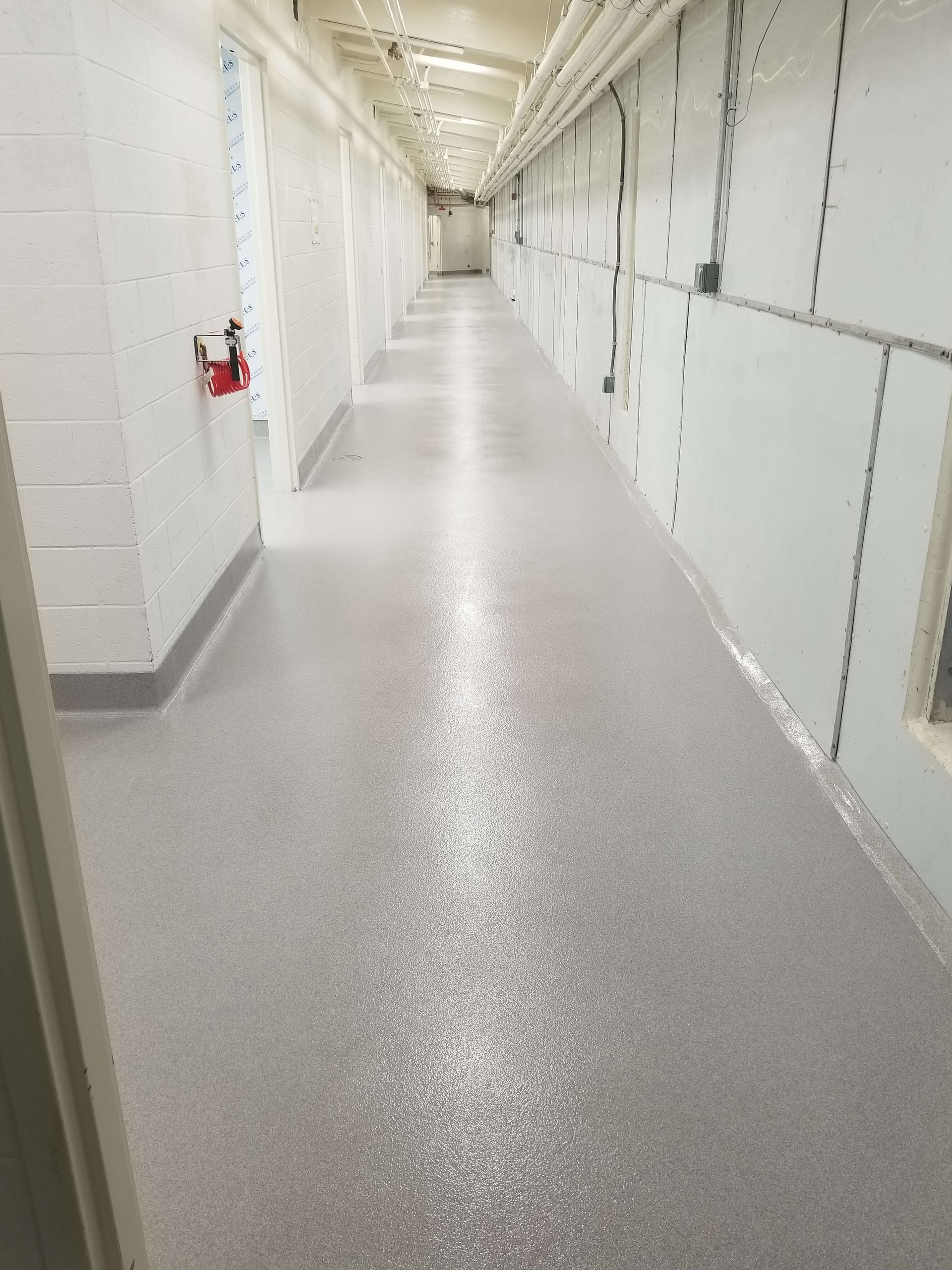 A long hallway in a building with a fire extinguisher on the wall.