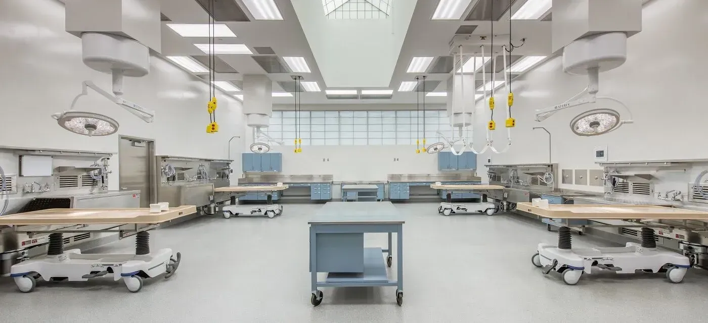 Anatomy lab with several tables, lights, and equipment in a bright, modern room.