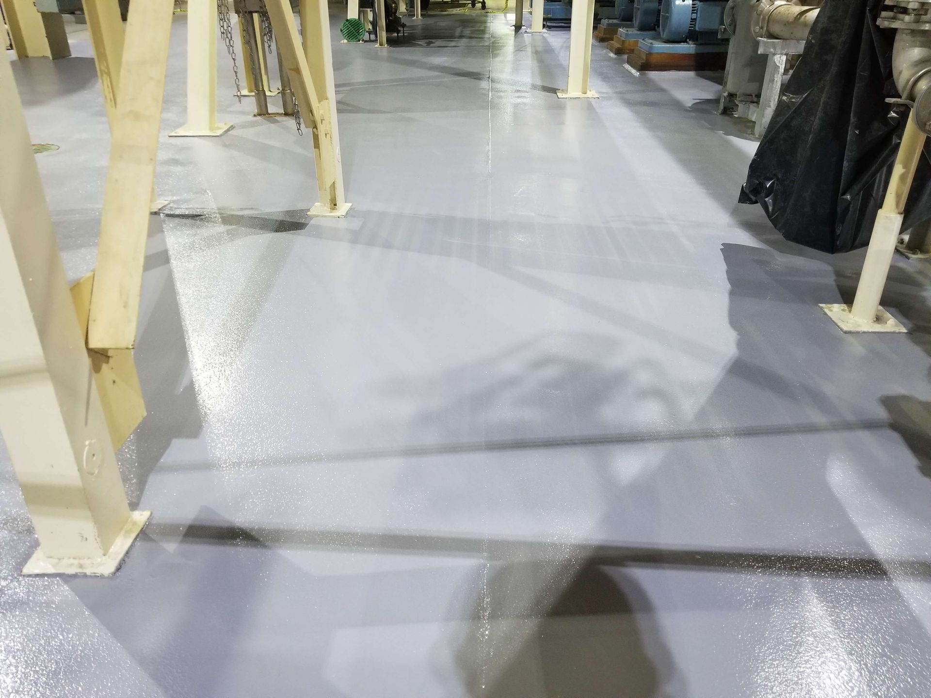 A gray concrete floor in a factory with a lot of pillars.