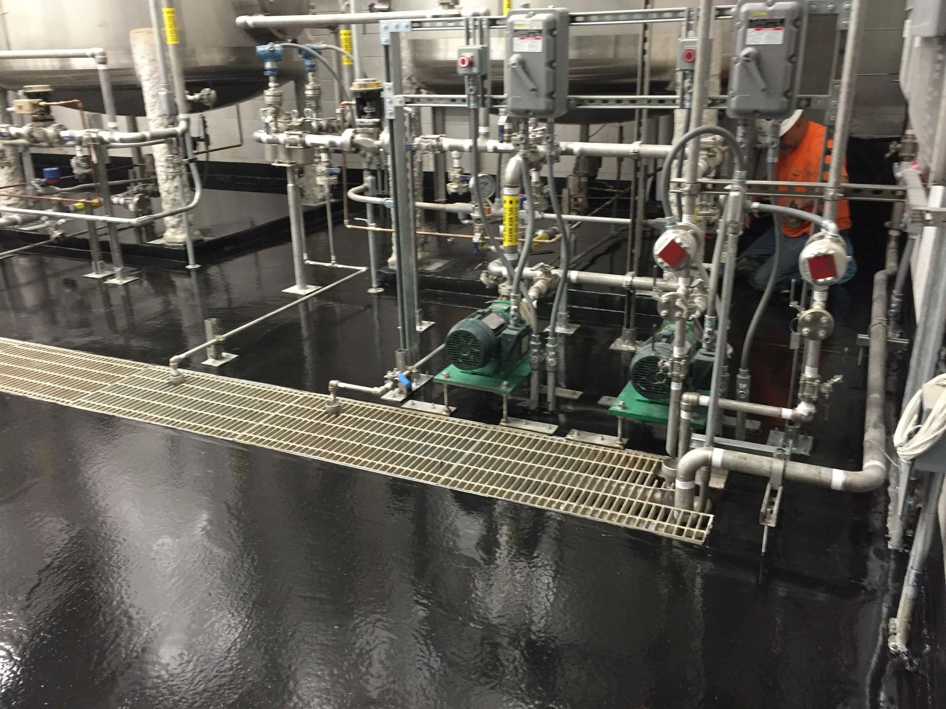 A man is standing in a room filled with pipes and pumps.