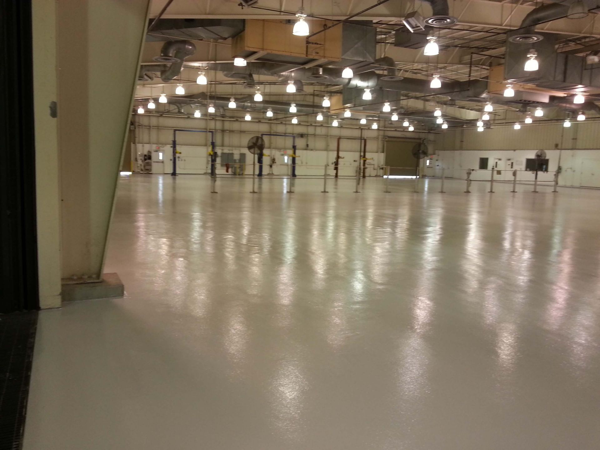 A large empty warehouse with a lot of lights on the ceiling.