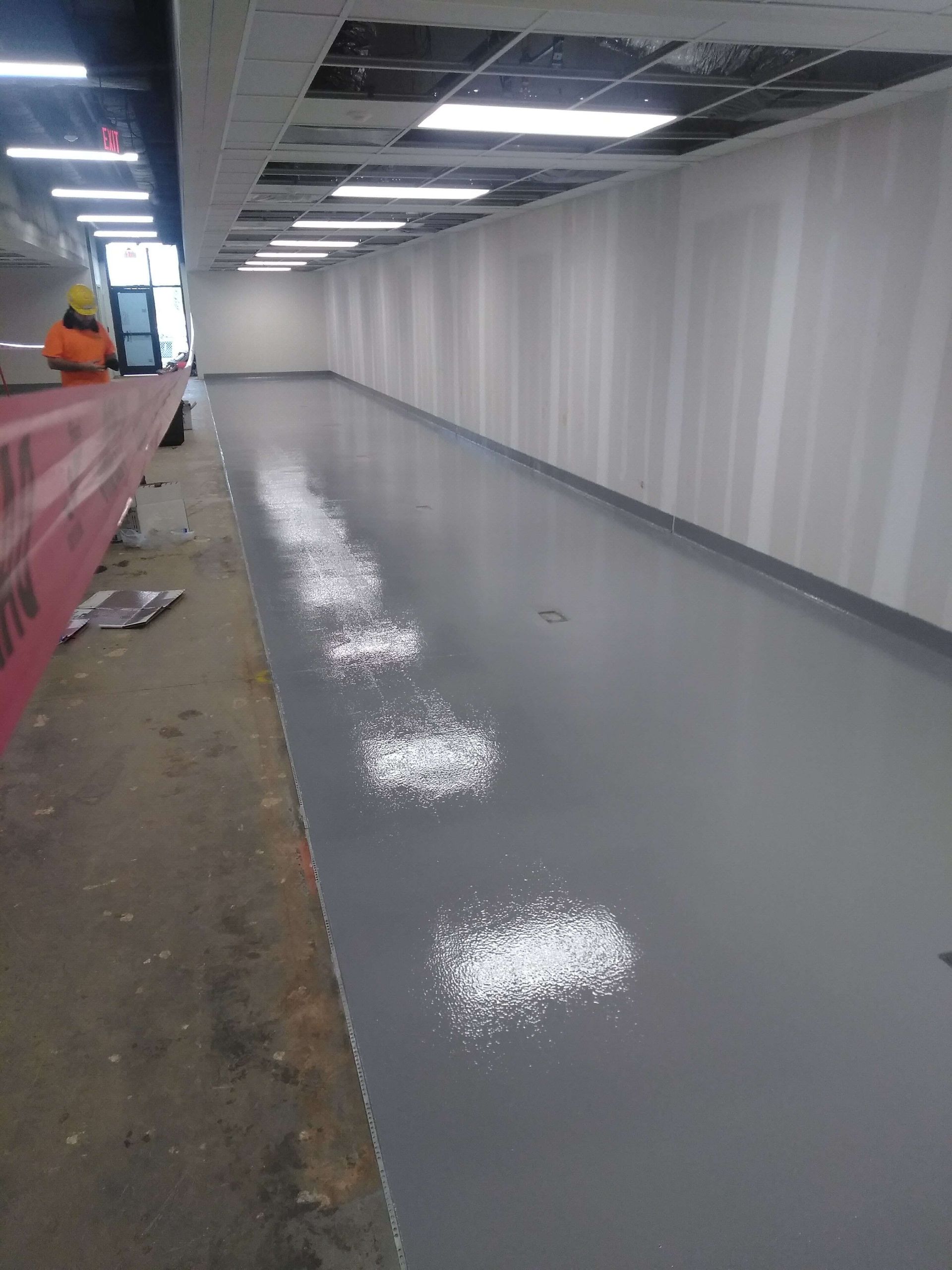 A long empty hallway with a lot of lights on the ceiling.