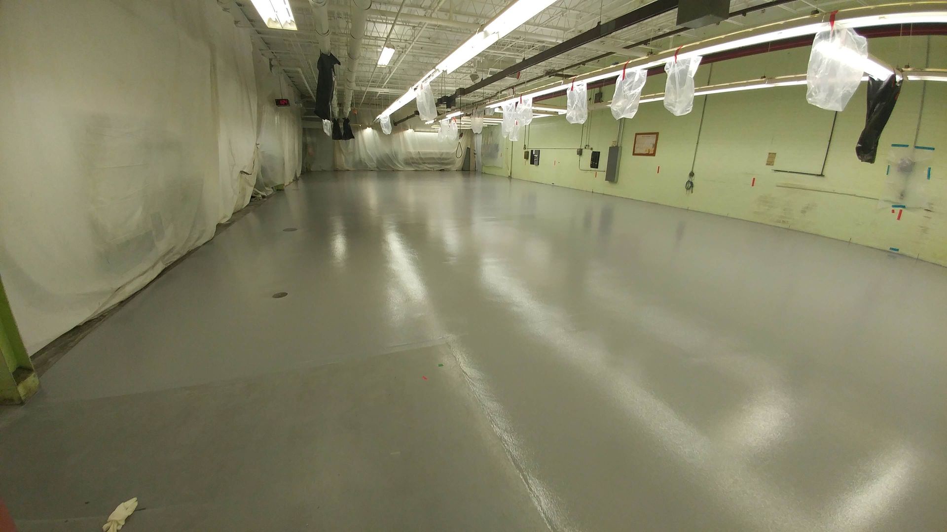 A large empty room with a gray floor and green walls.