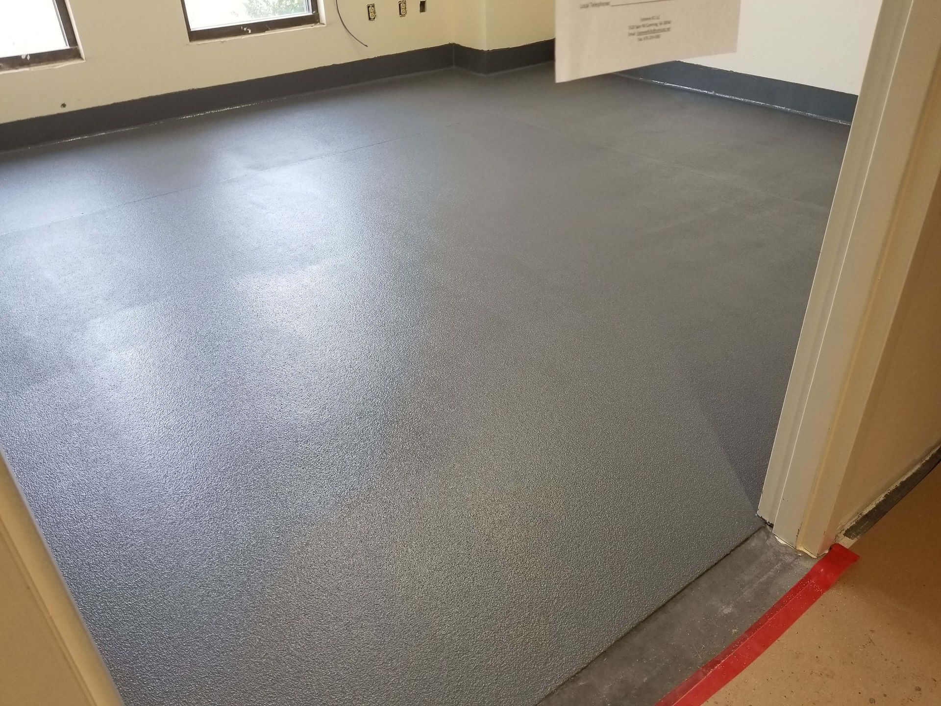 A room with a gray floor and a door that is open