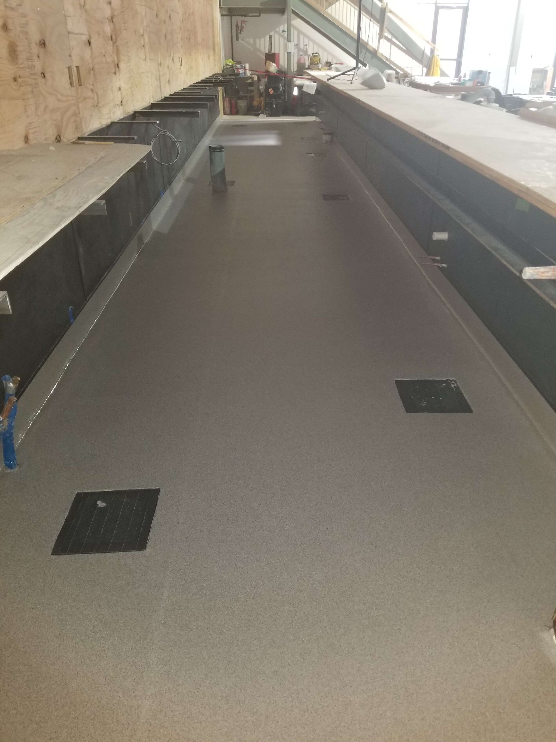 A long hallway with a concrete floor in a building.