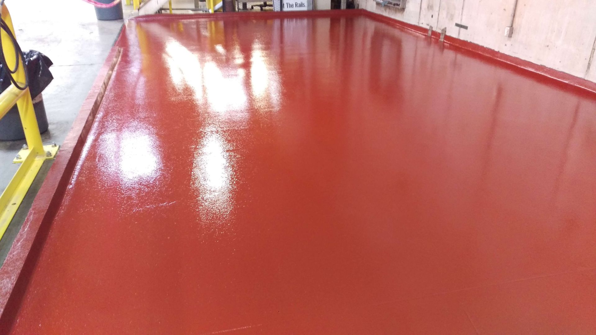 A red floor in a building with a yellow railing.