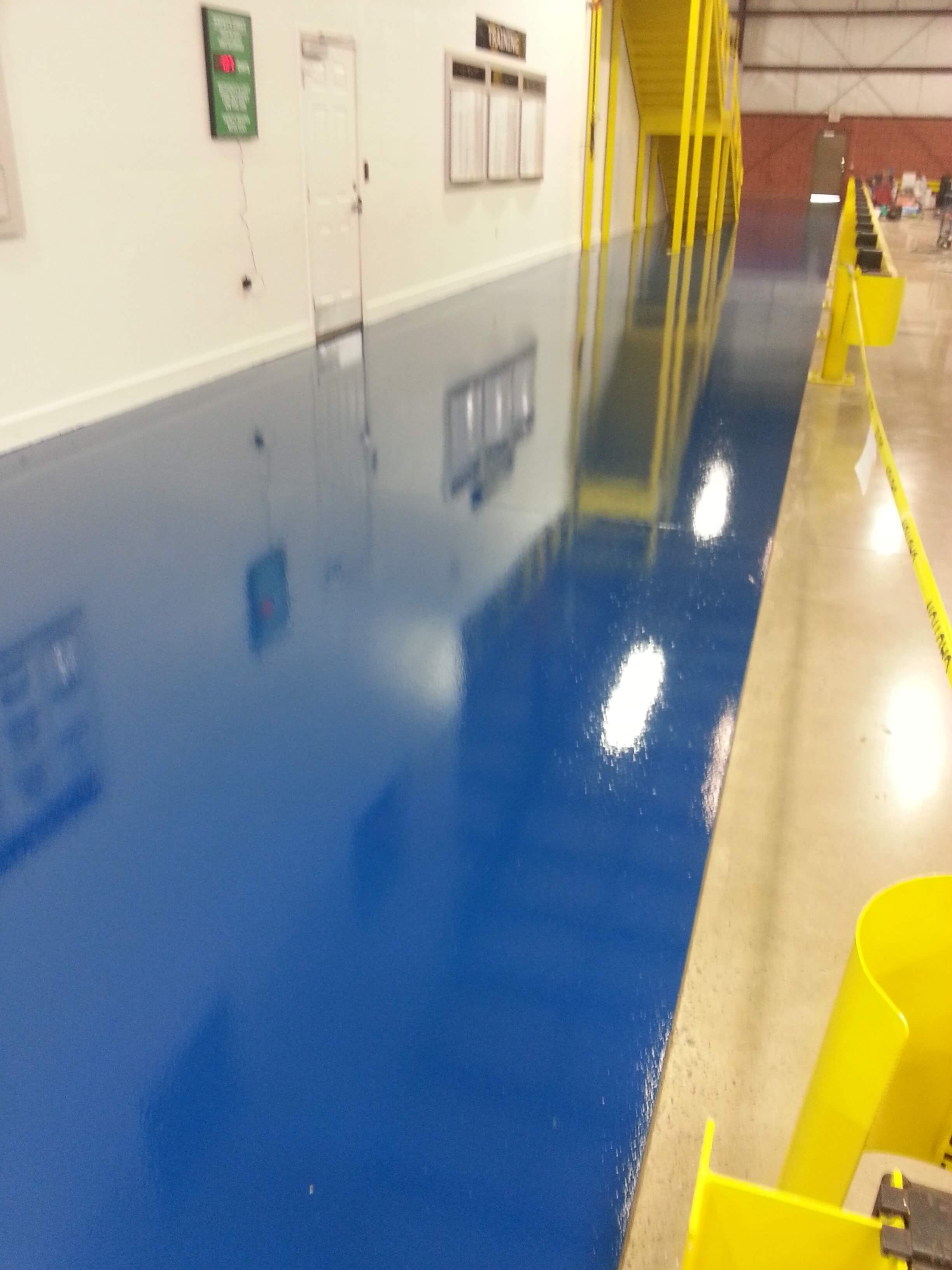 A warehouse with a blue floor and yellow barriers