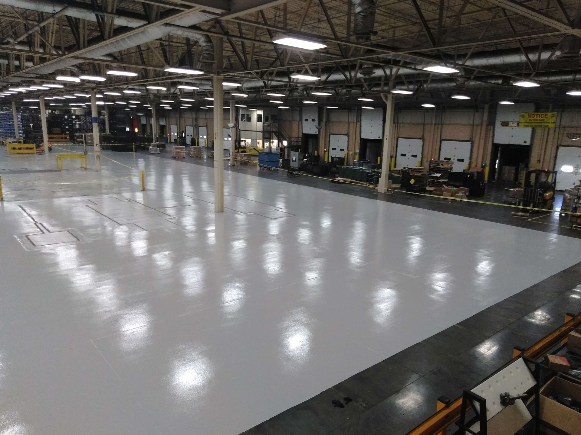 A large warehouse with a white floor and lots of lights.