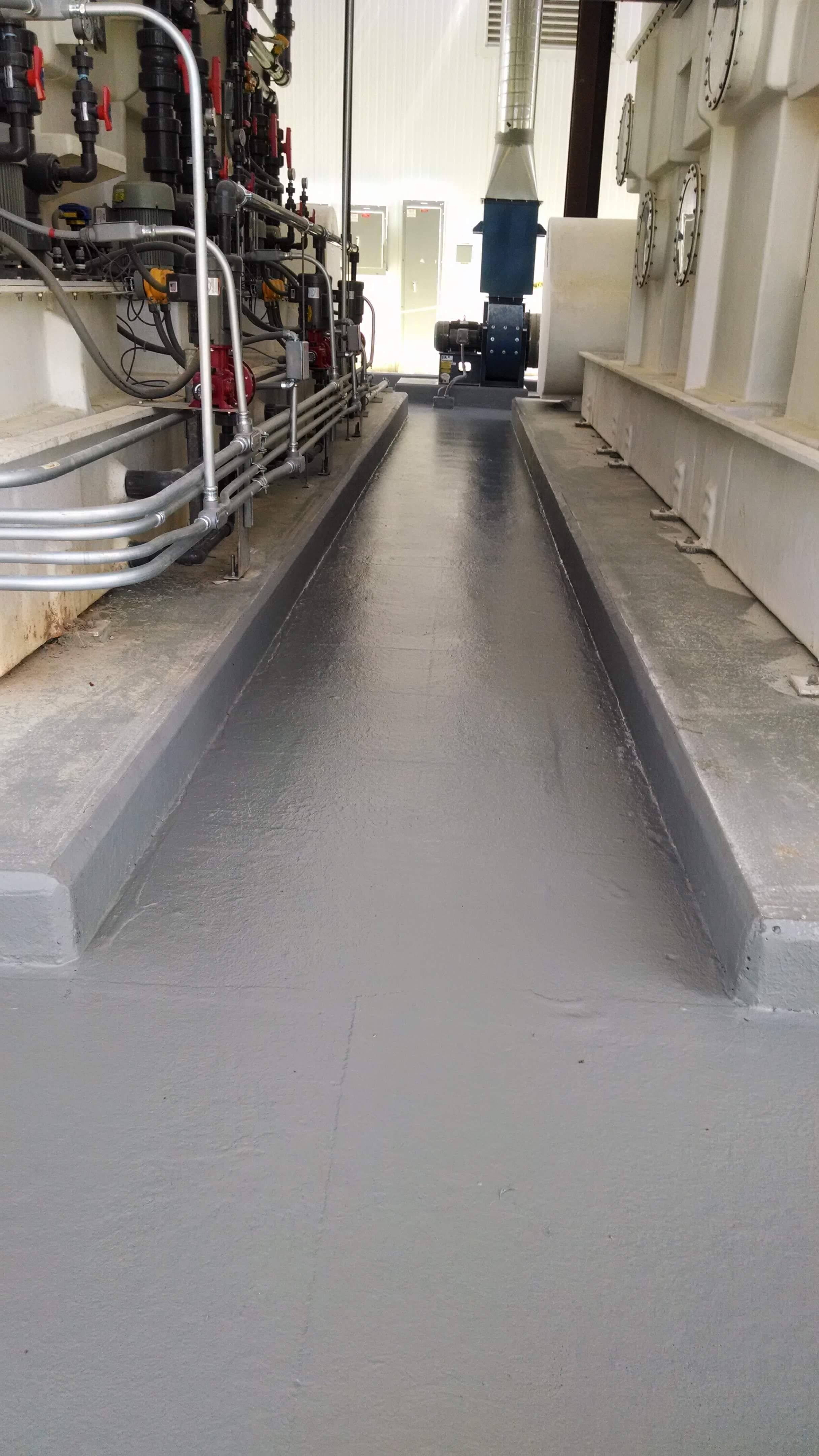 A very long hallway in a factory with a lot of pipes and pumps.