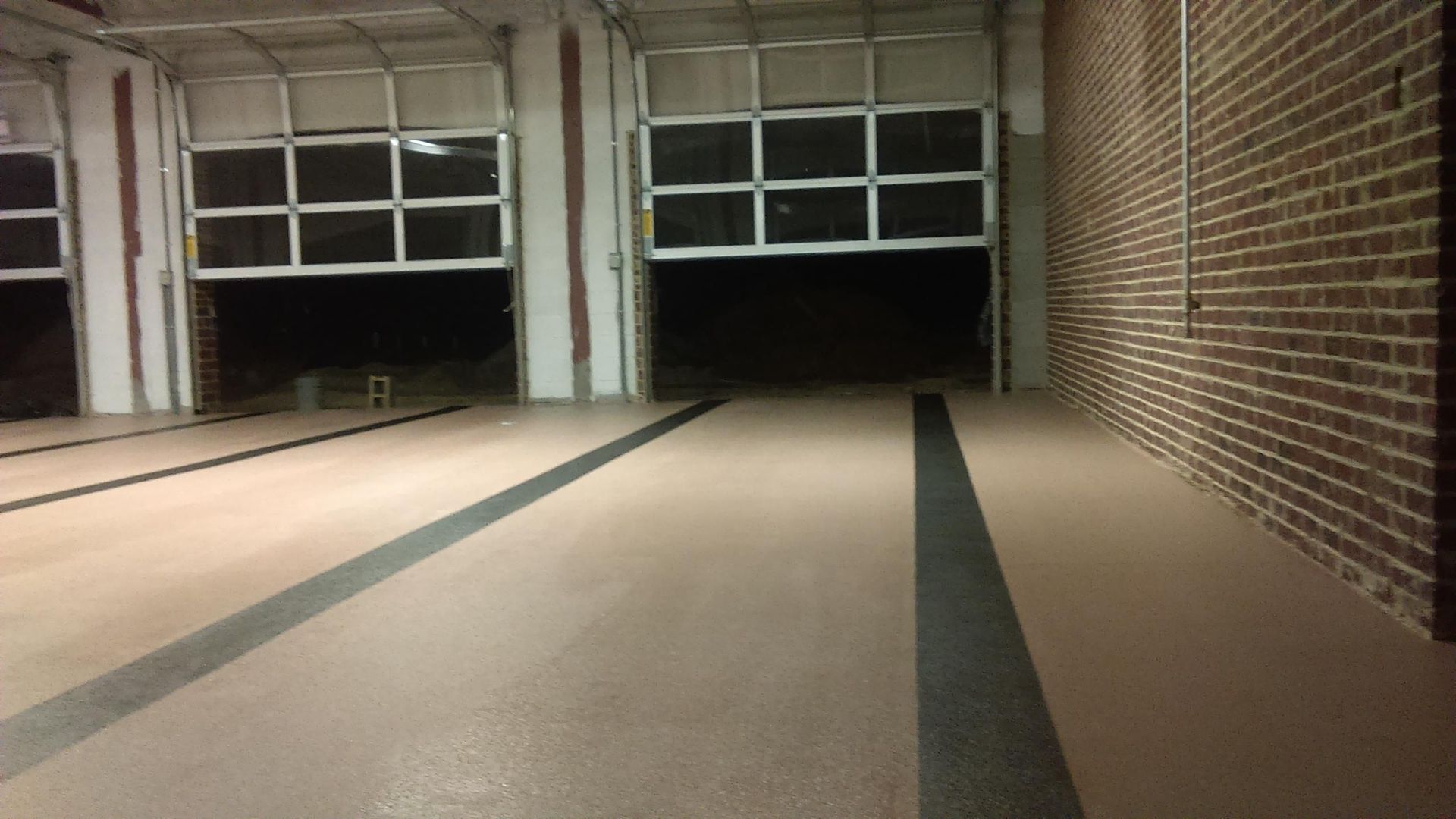 An empty garage with a brick wall and a large garage door