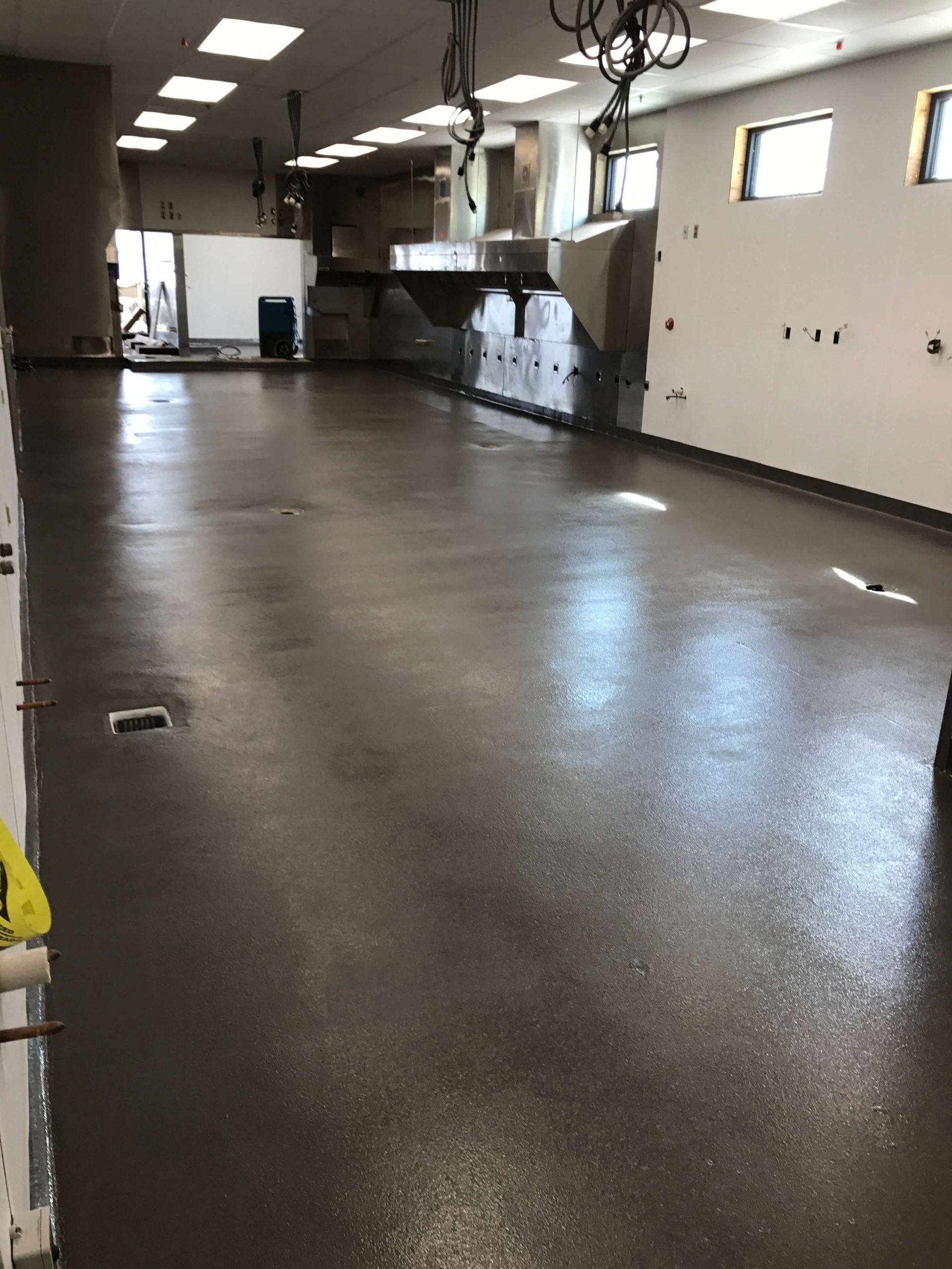 A large empty room with a brown floor and white walls.