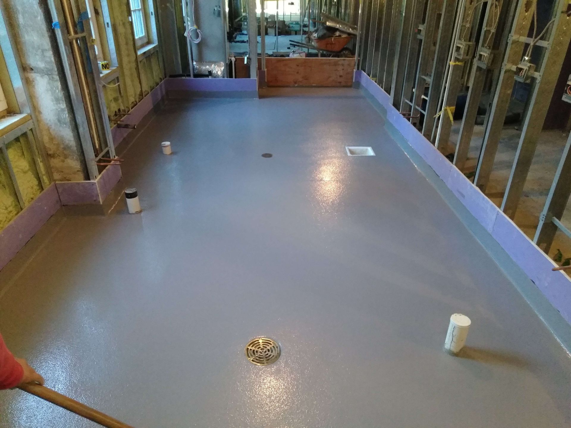 A large room with a gray floor and a red broom.