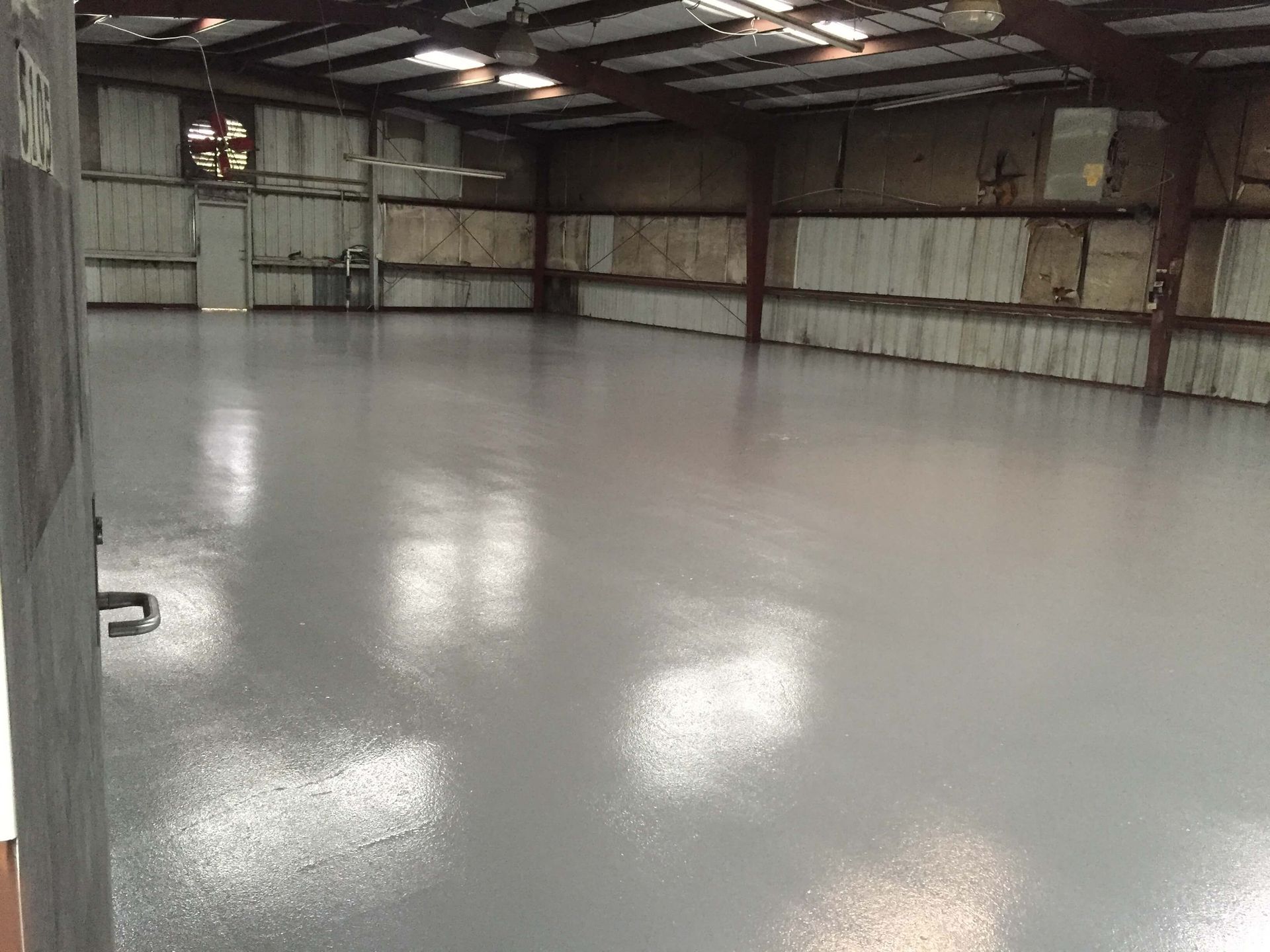 A large warehouse with a concrete floor and a ceiling fan.