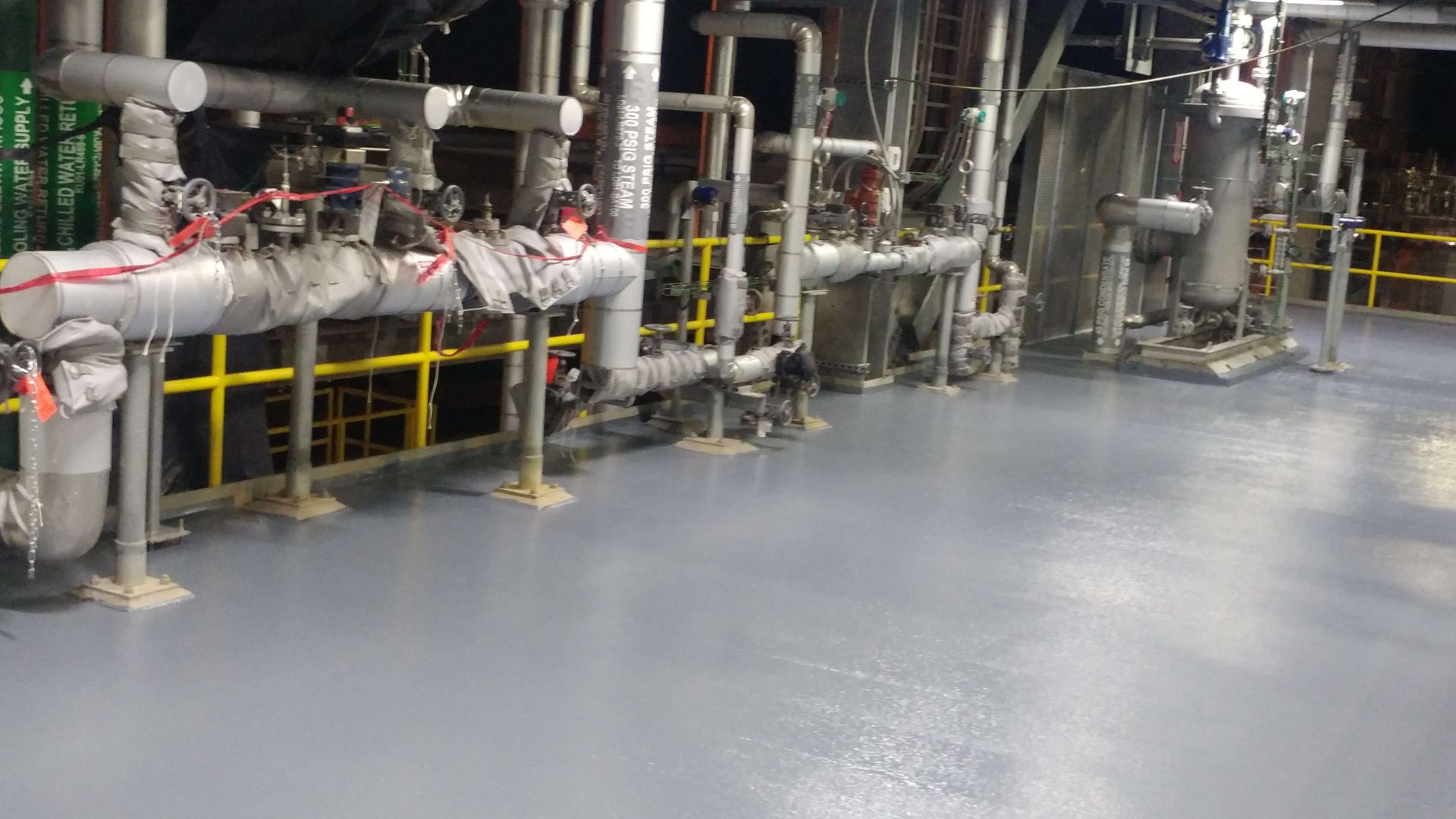 A factory with a lot of pipes and valves on the floor.