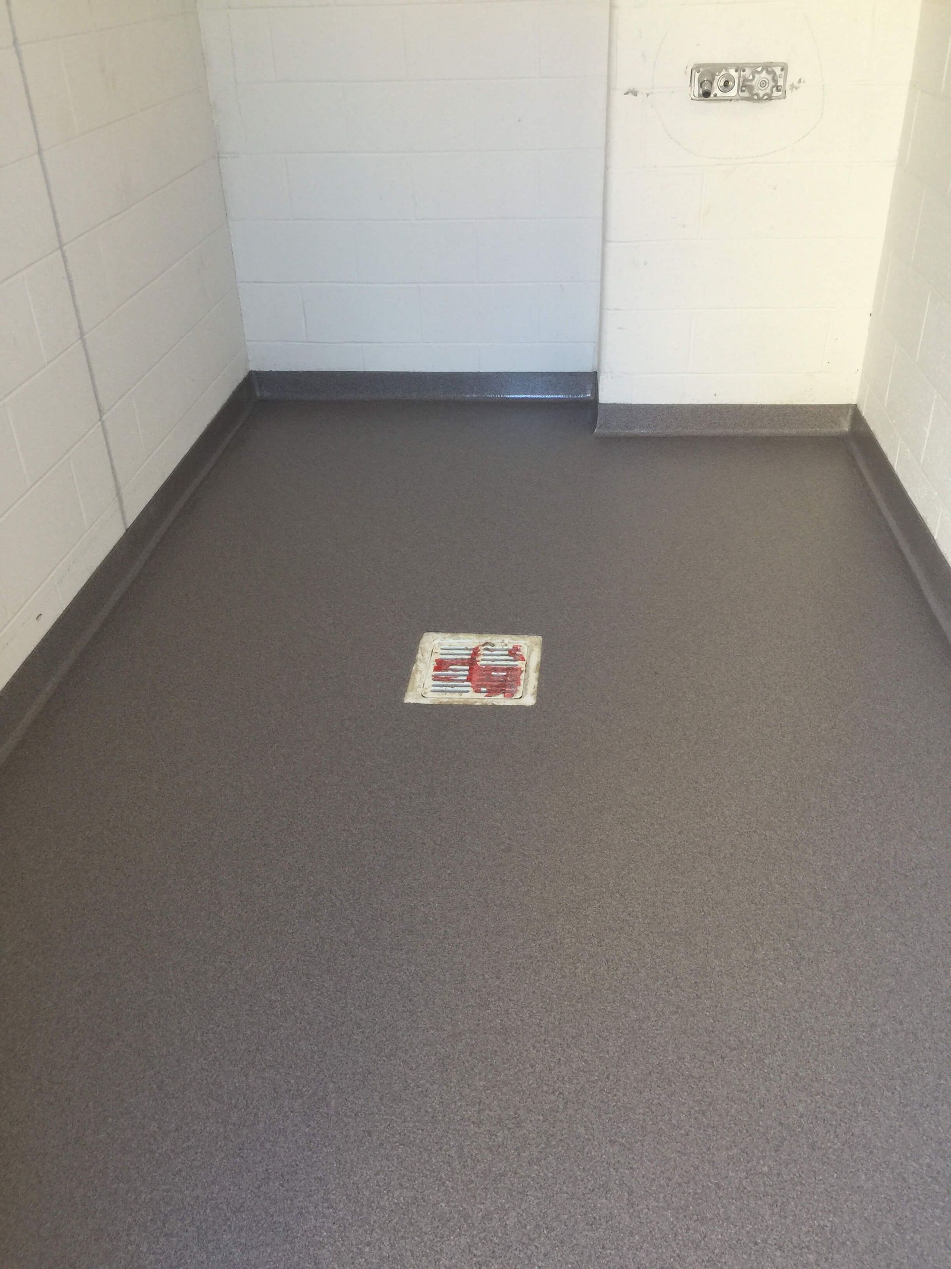 A room with a gray floor and a white wall.