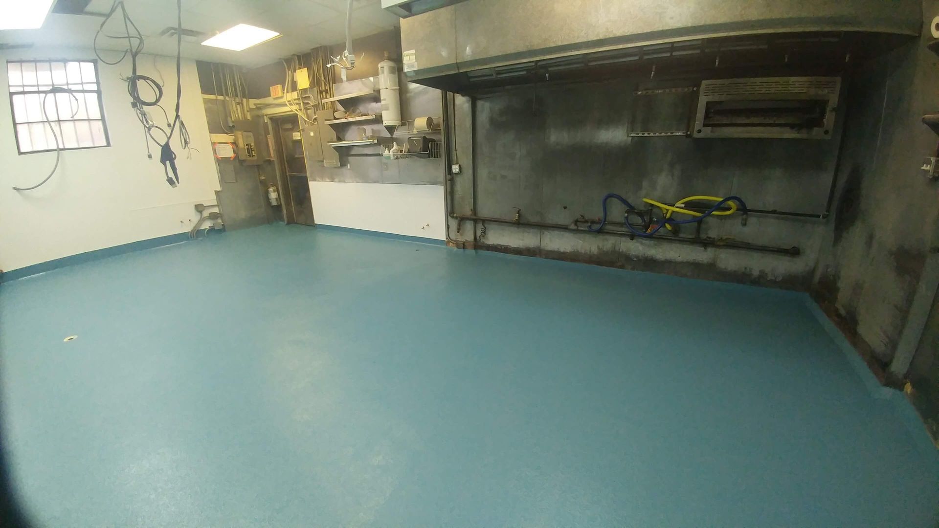 A kitchen with a blue floor and a stainless steel hood.