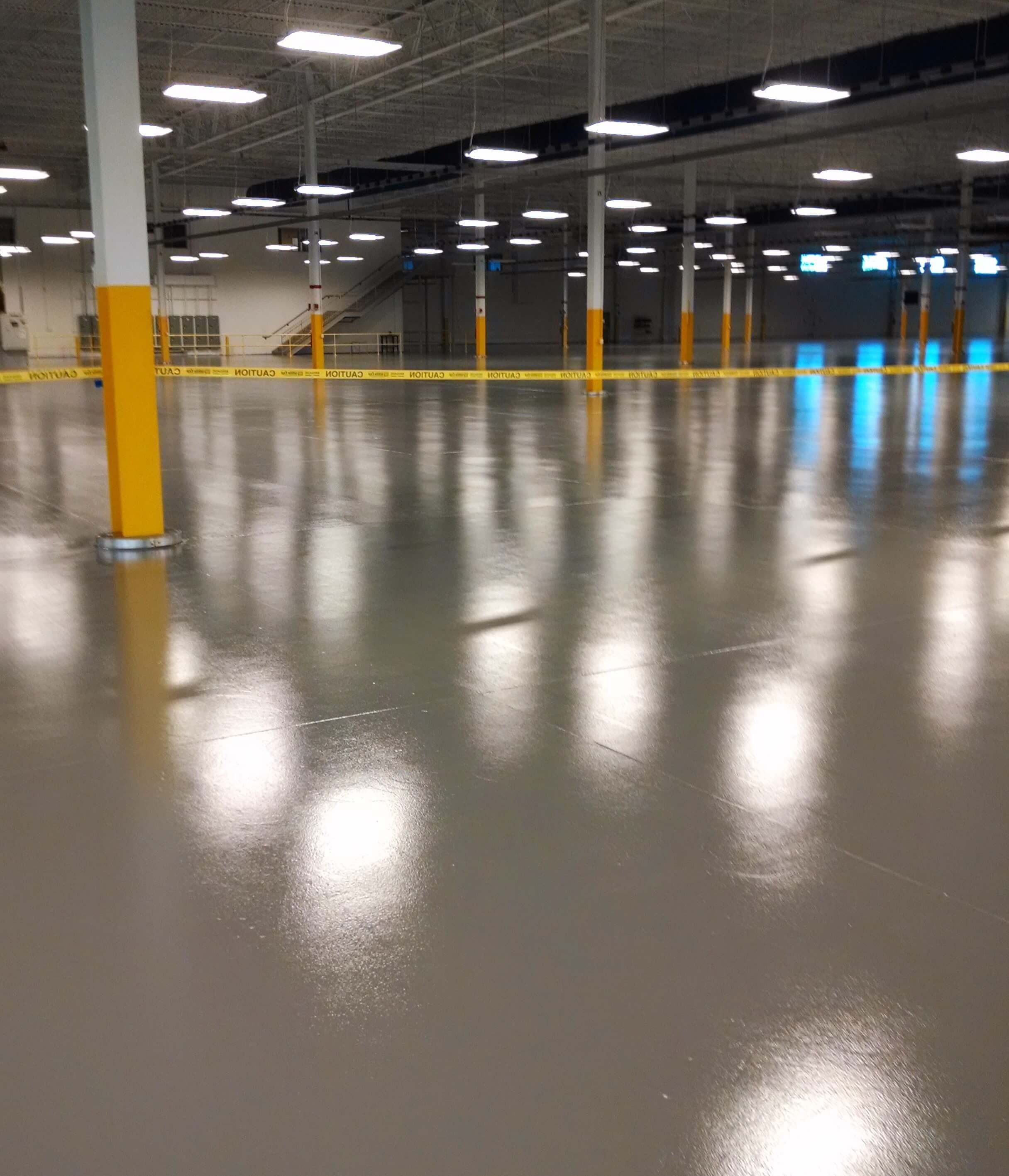 A large empty warehouse with a shiny floor and columns.