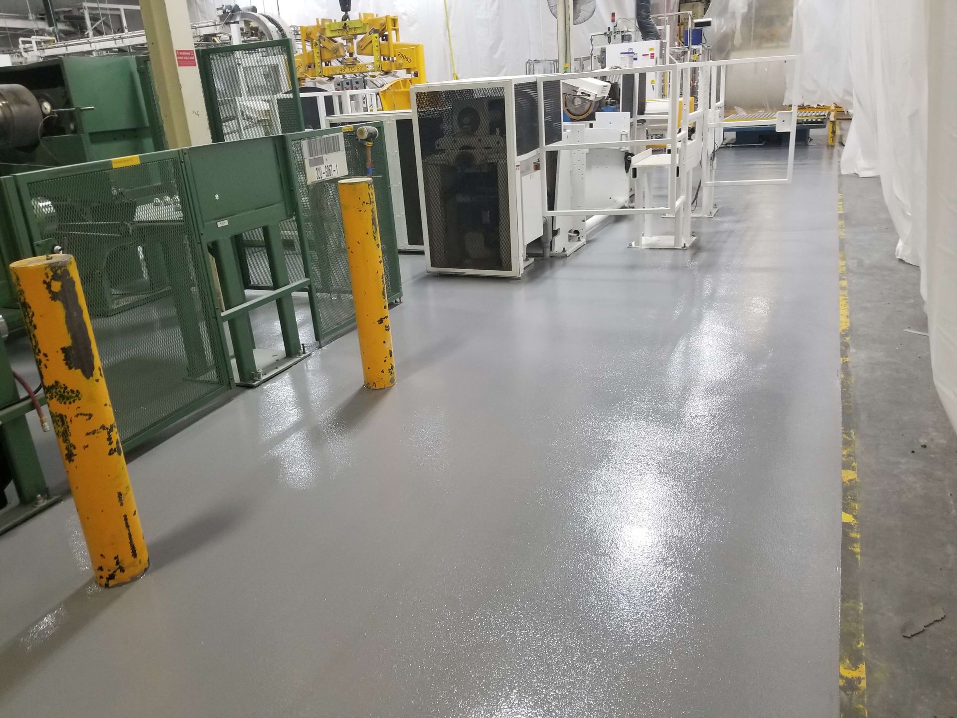 A warehouse with a gray floor and yellow poles.