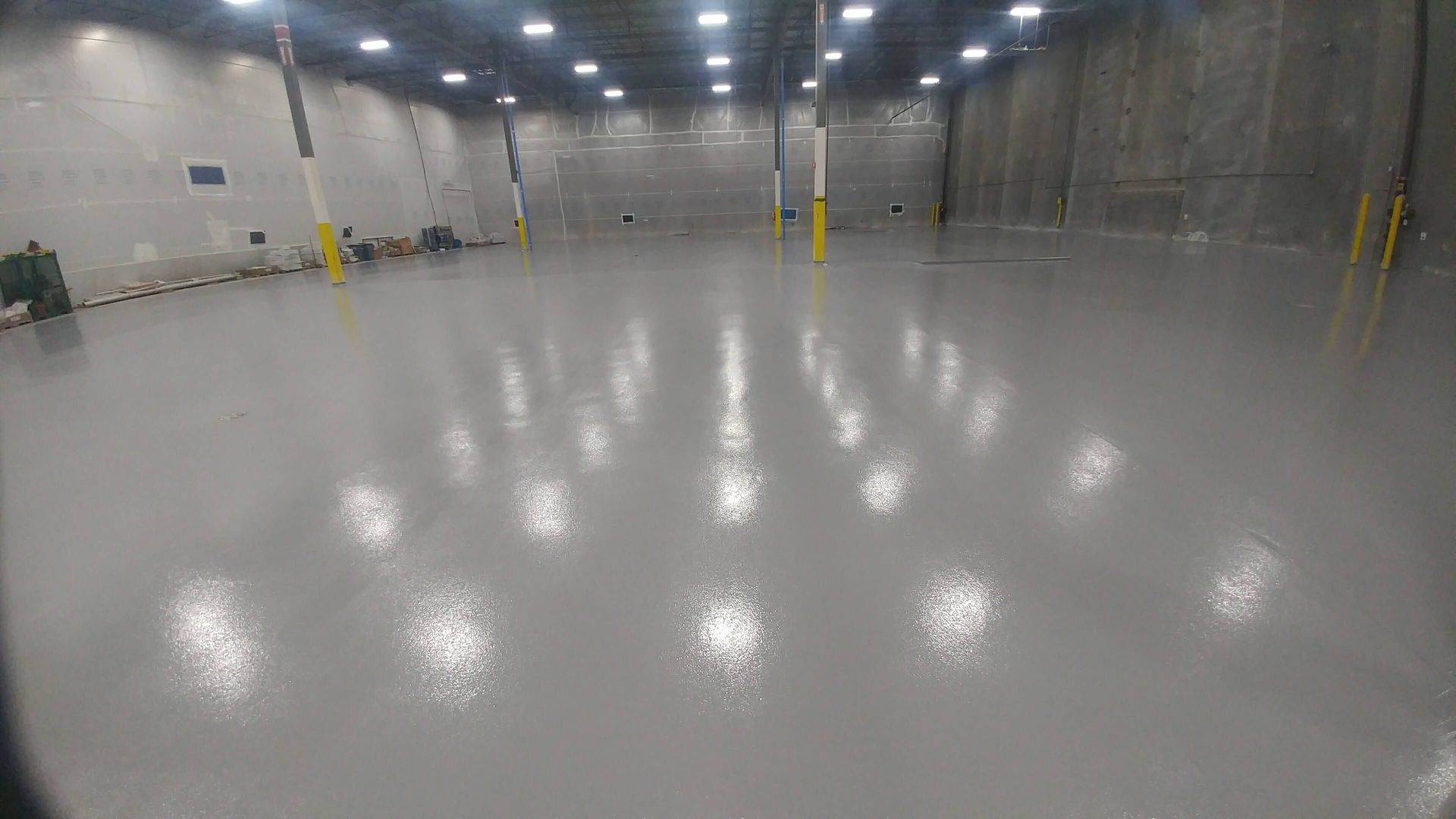 A large warehouse with a shiny concrete floor and lots of lights.