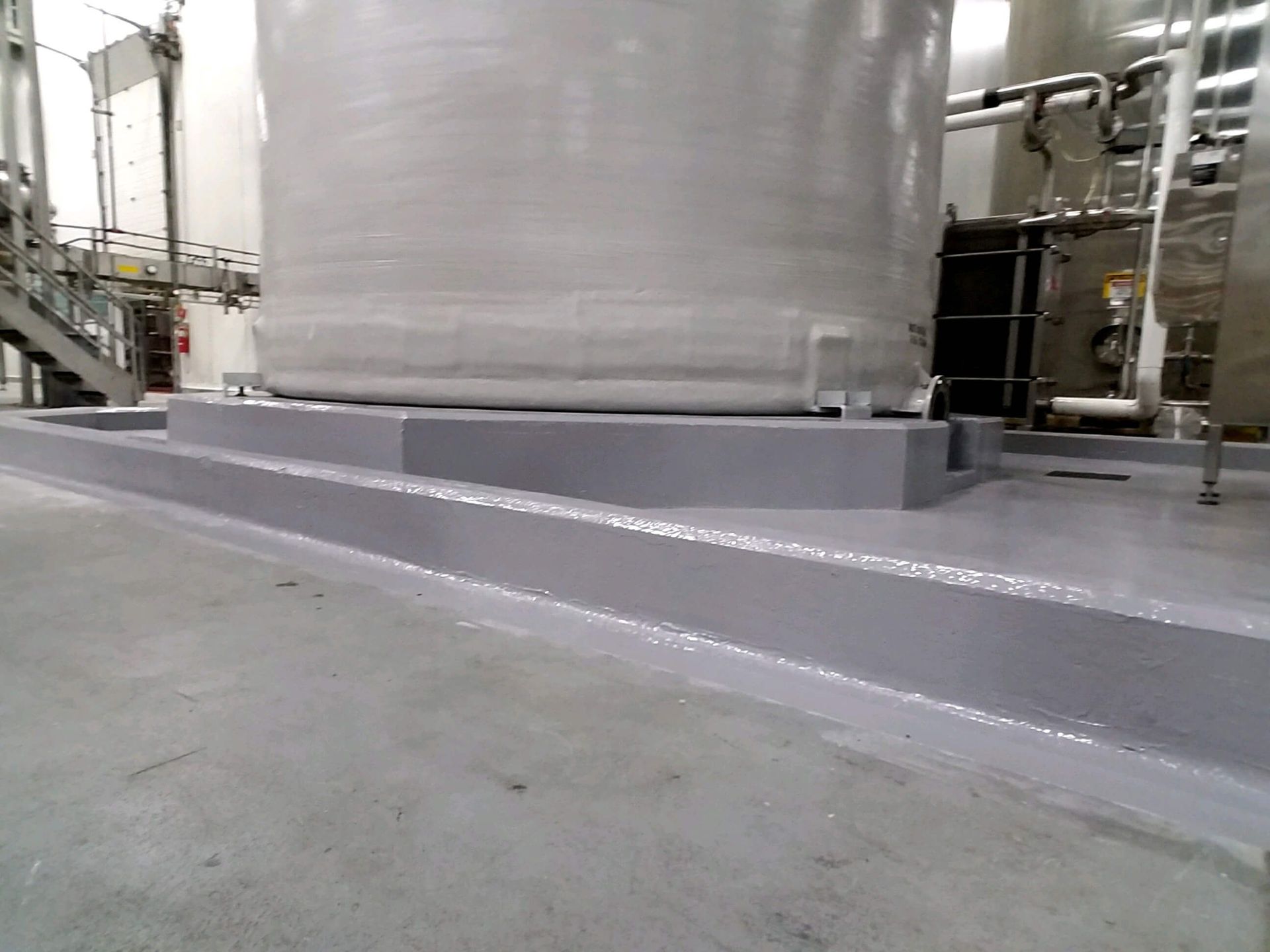 A large tank is sitting on top of a concrete platform in a factory.