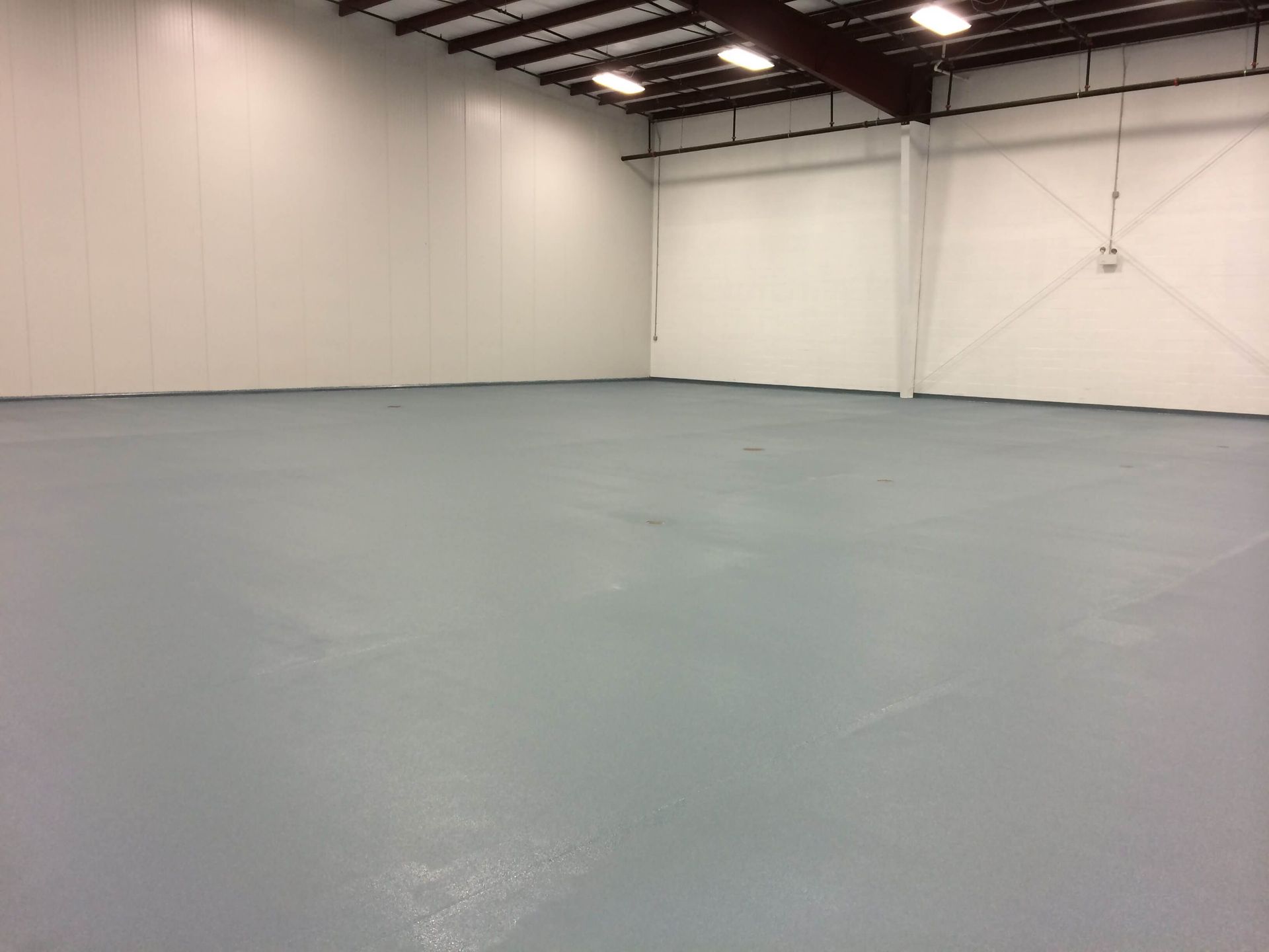 An empty warehouse with a gray floor and white walls
