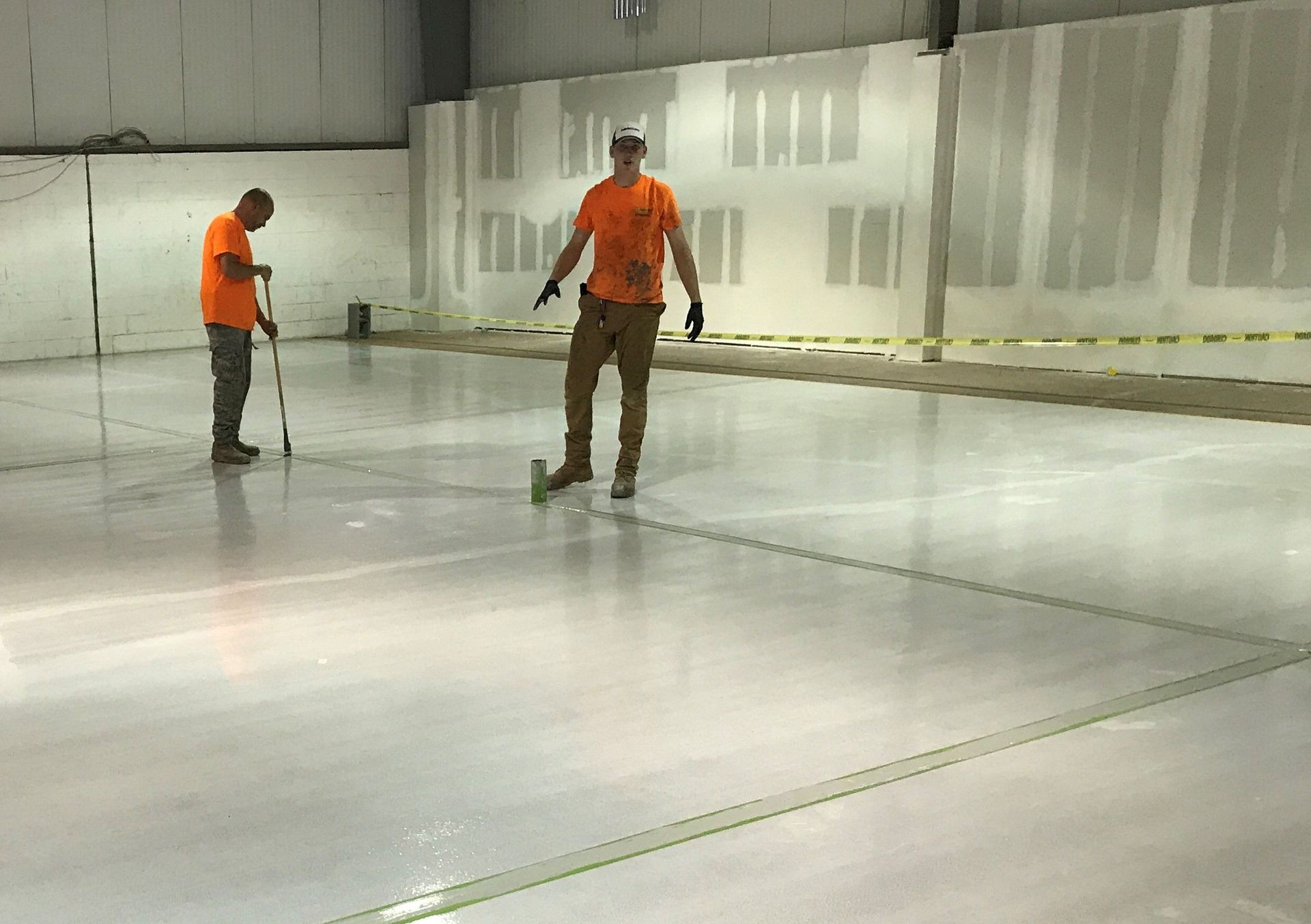 Two men are working on a concrete floor in a building.