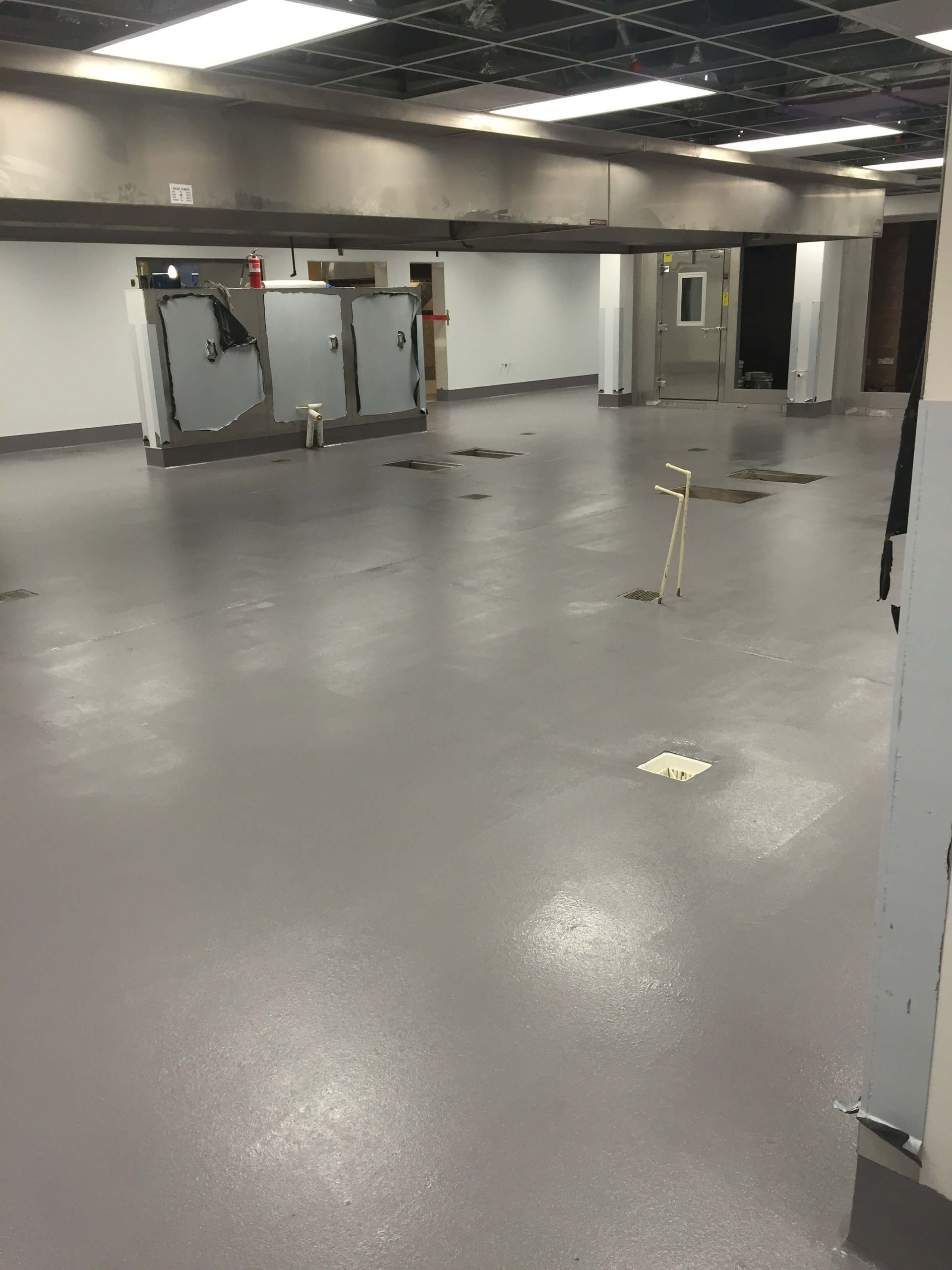 A large empty room with a gray floor and white walls.