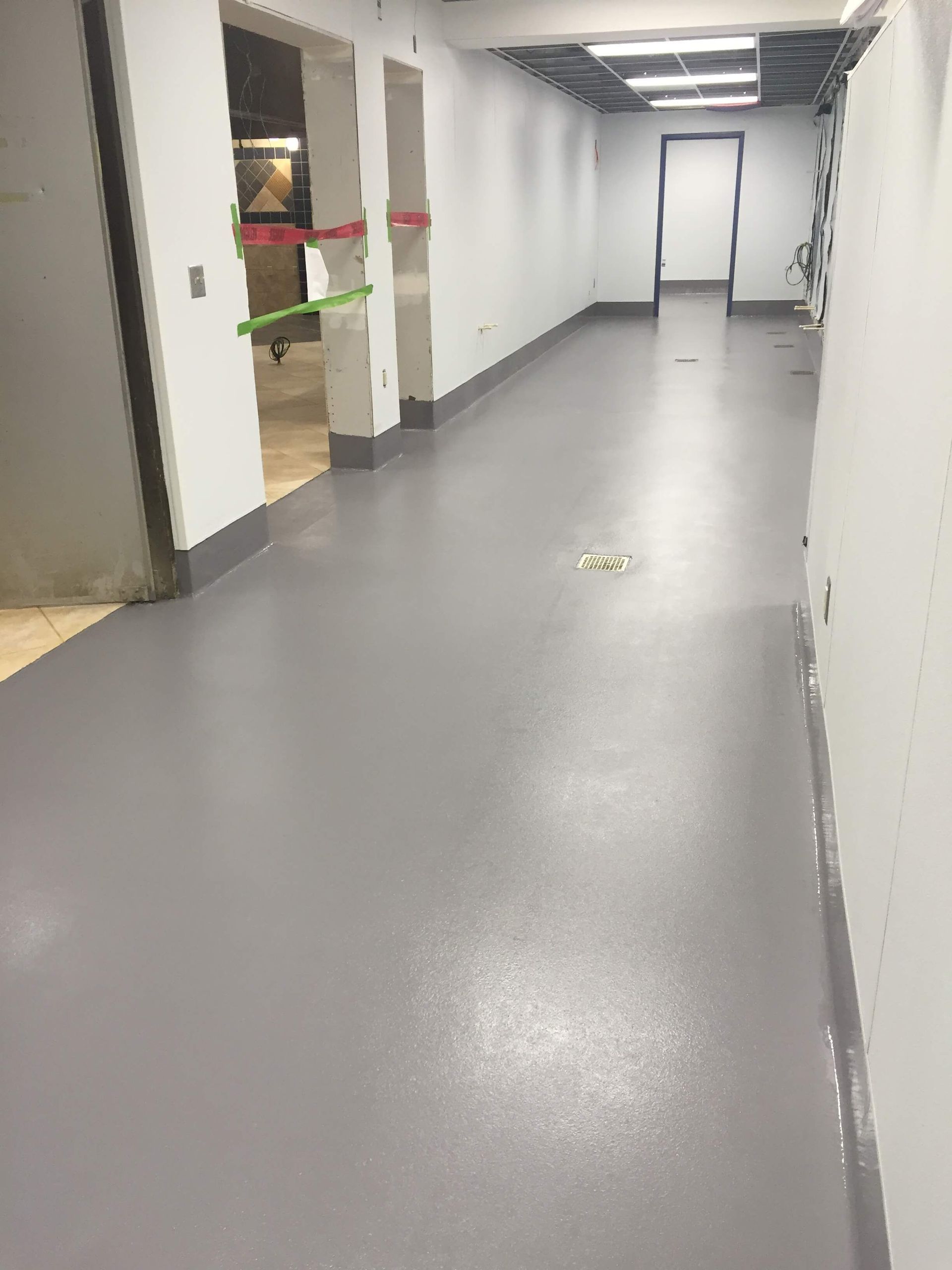 A long hallway with a gray floor and white walls.