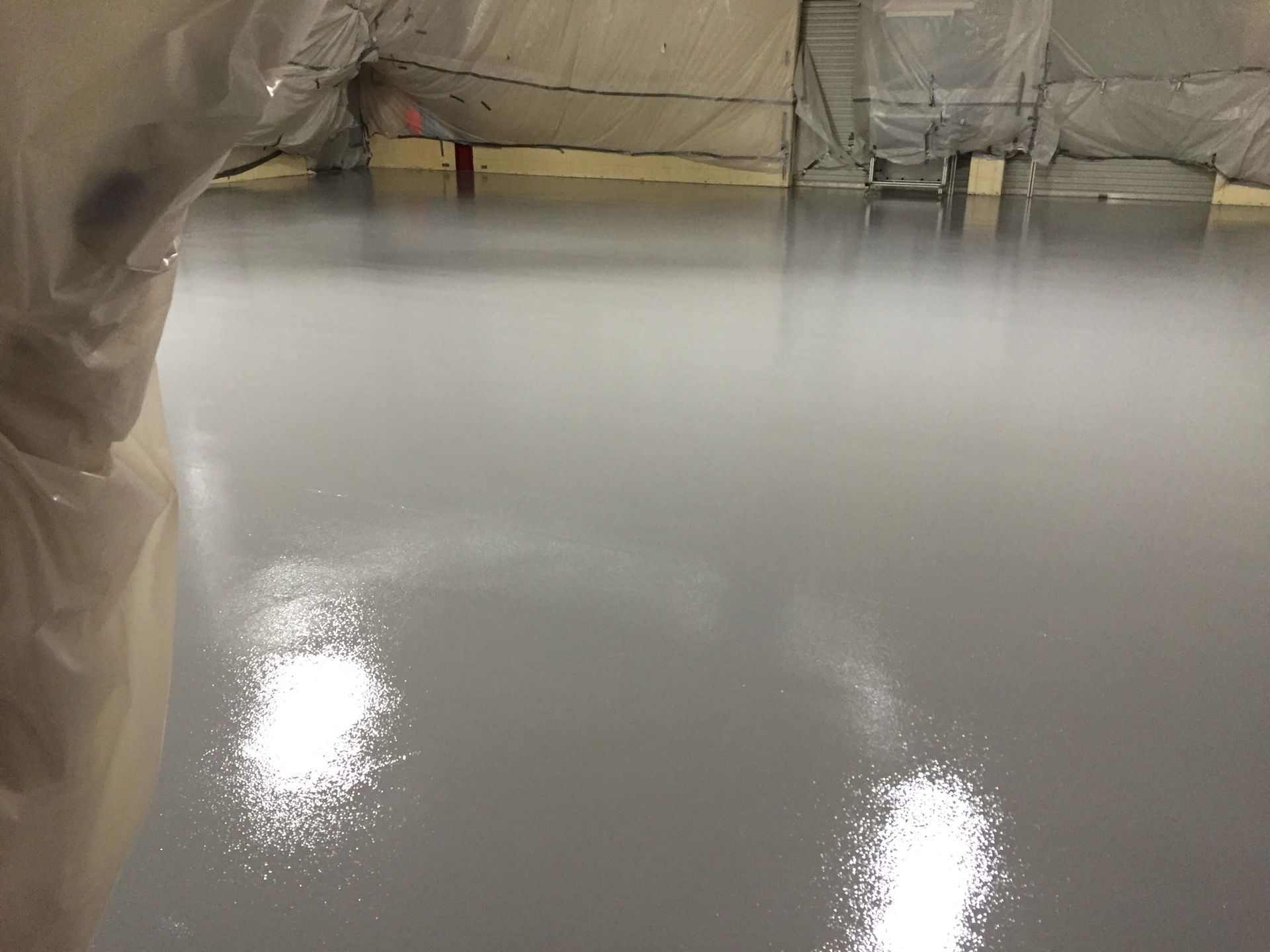 A shiny gray floor in a room with a ladder in the background.