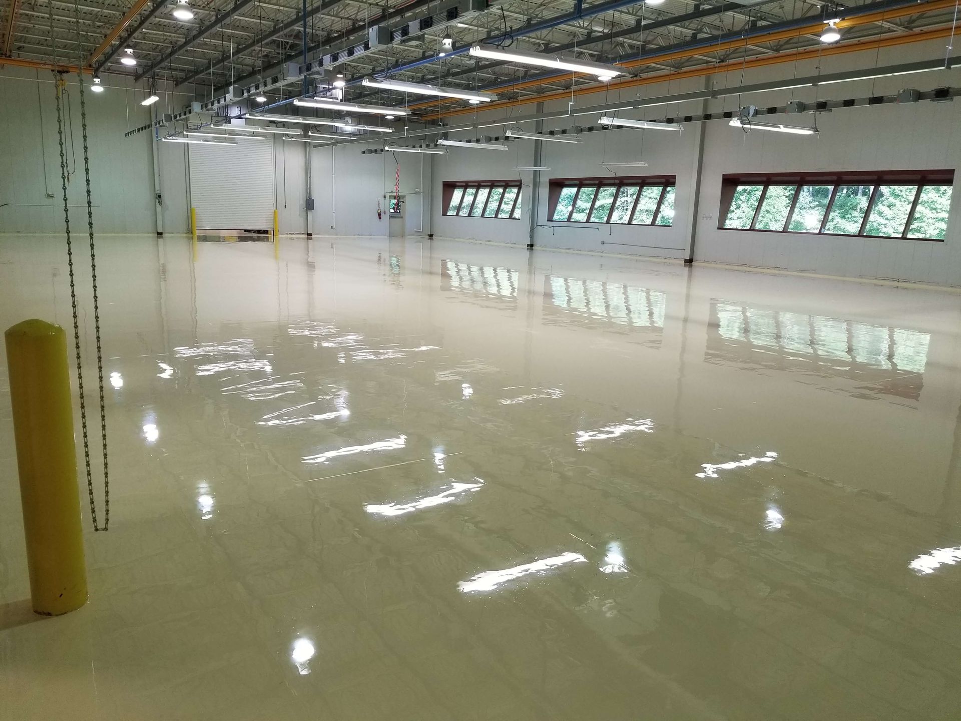 A large warehouse with a shiny floor and lots of windows.