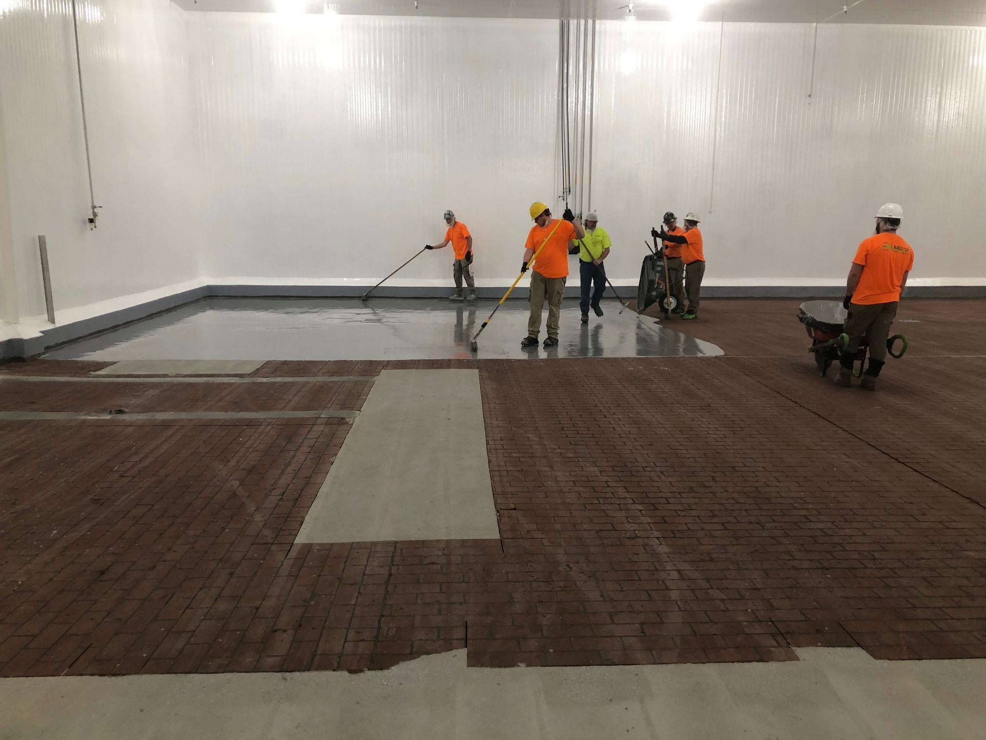 A group of men are working on a concrete floor in a large room.