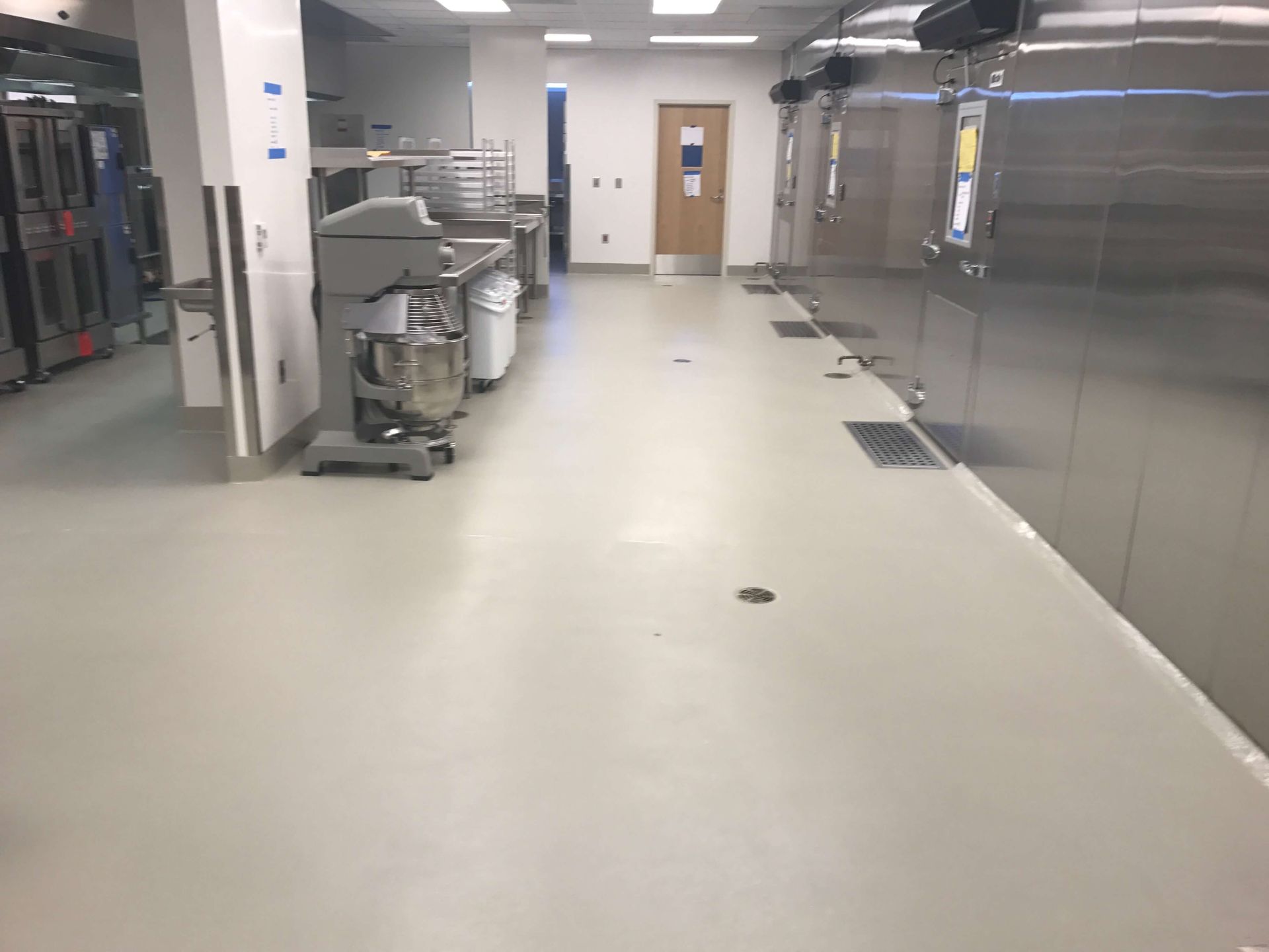 A long hallway in a kitchen with stainless steel appliances
