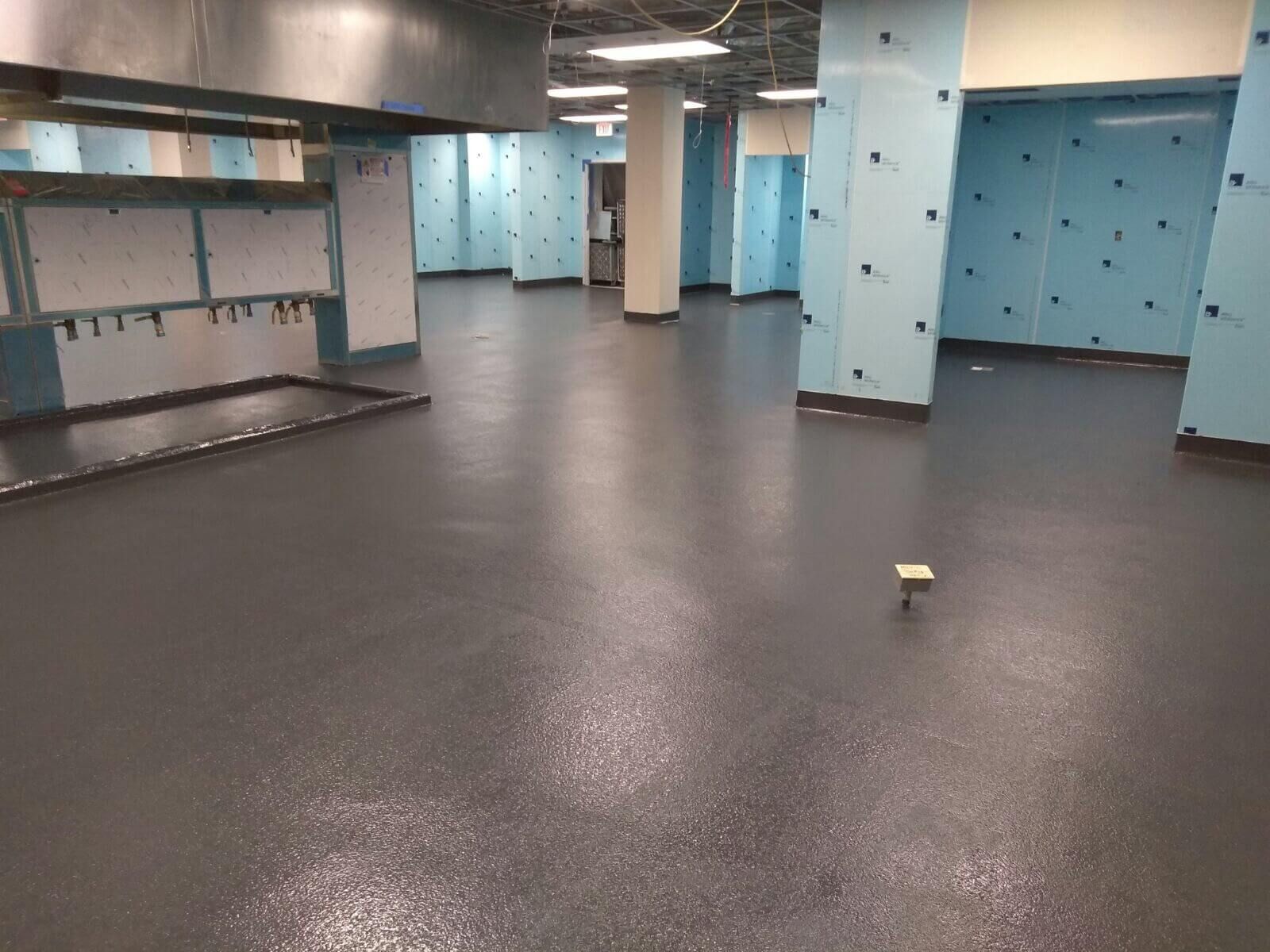 A large empty room with a black floor and blue walls.