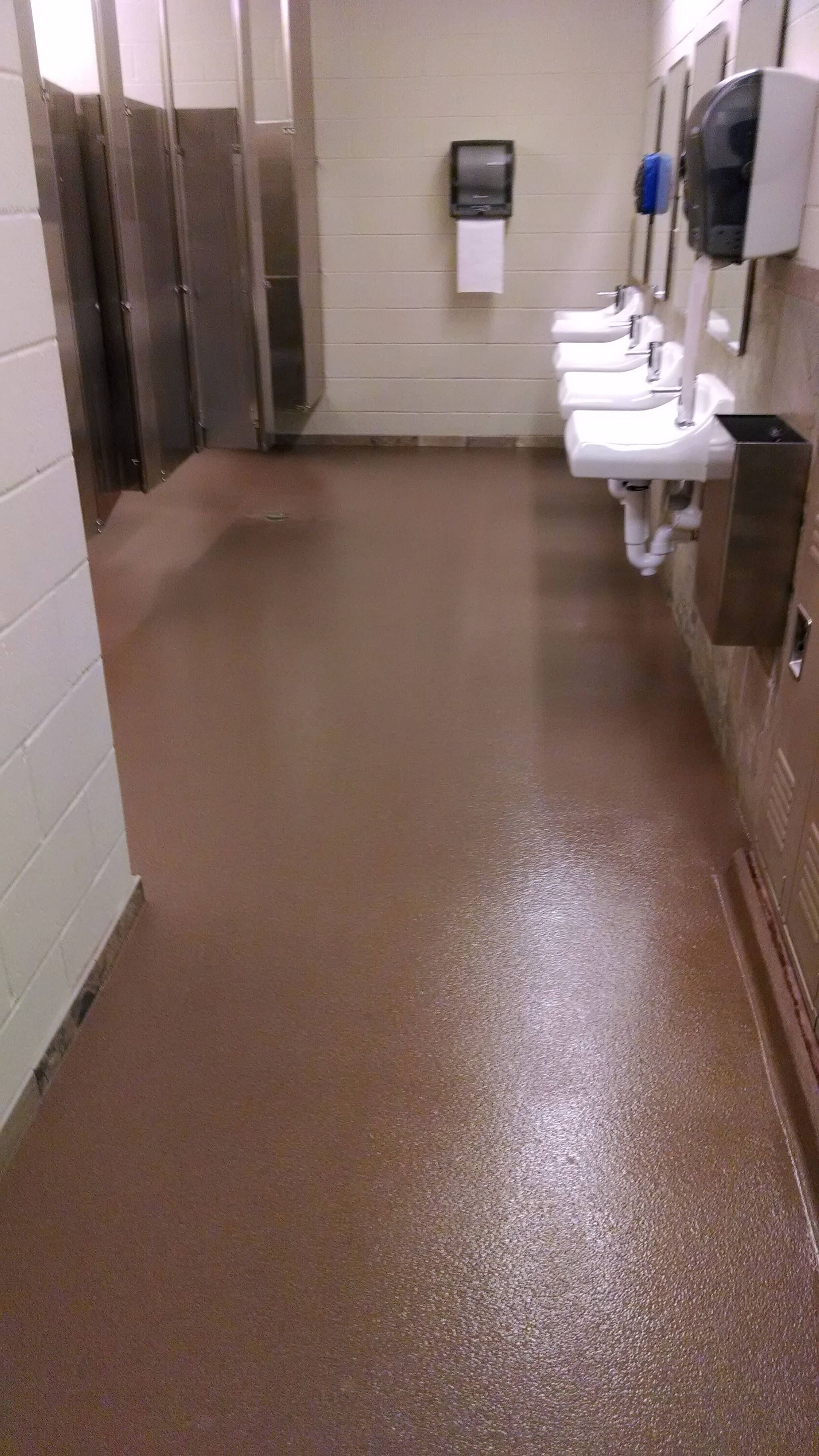 Public restroom with brown speckled floor, sinks, and stalls.