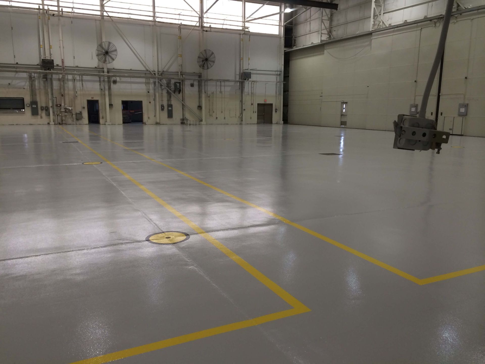 Gray industrial space with yellow floor markings, and a hoist.