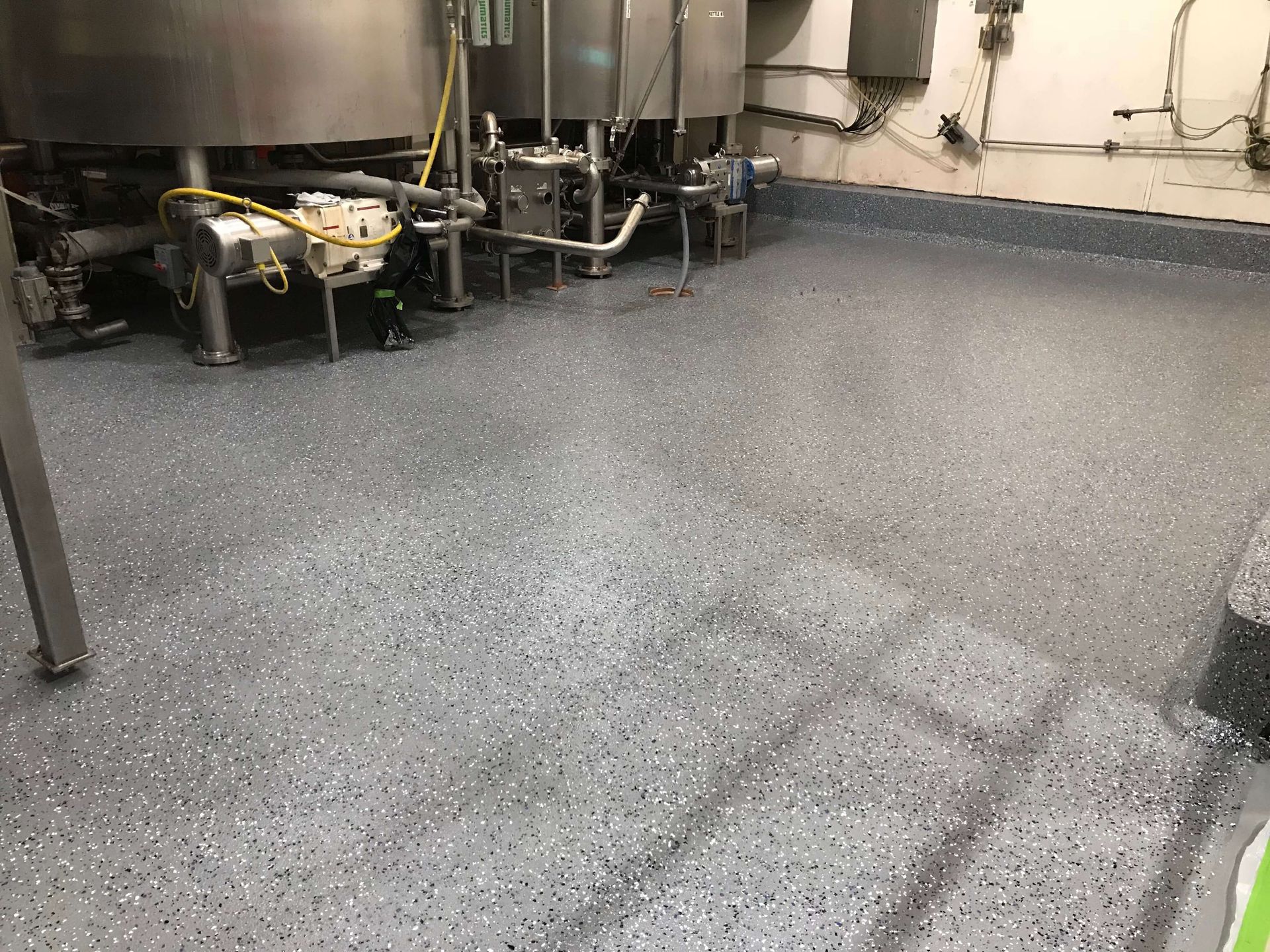 A large room with a gray floor and a lot of pipes.