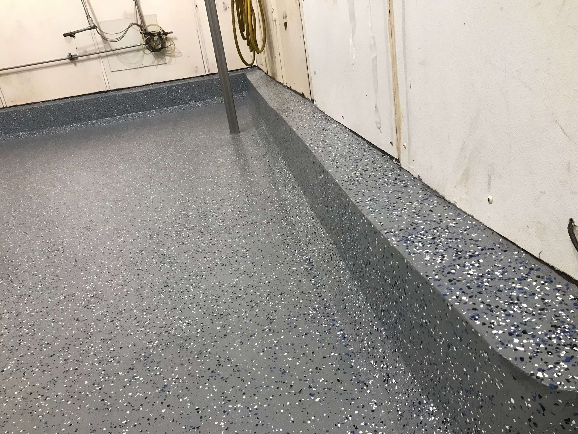 A room with a gray floor and a white wall.