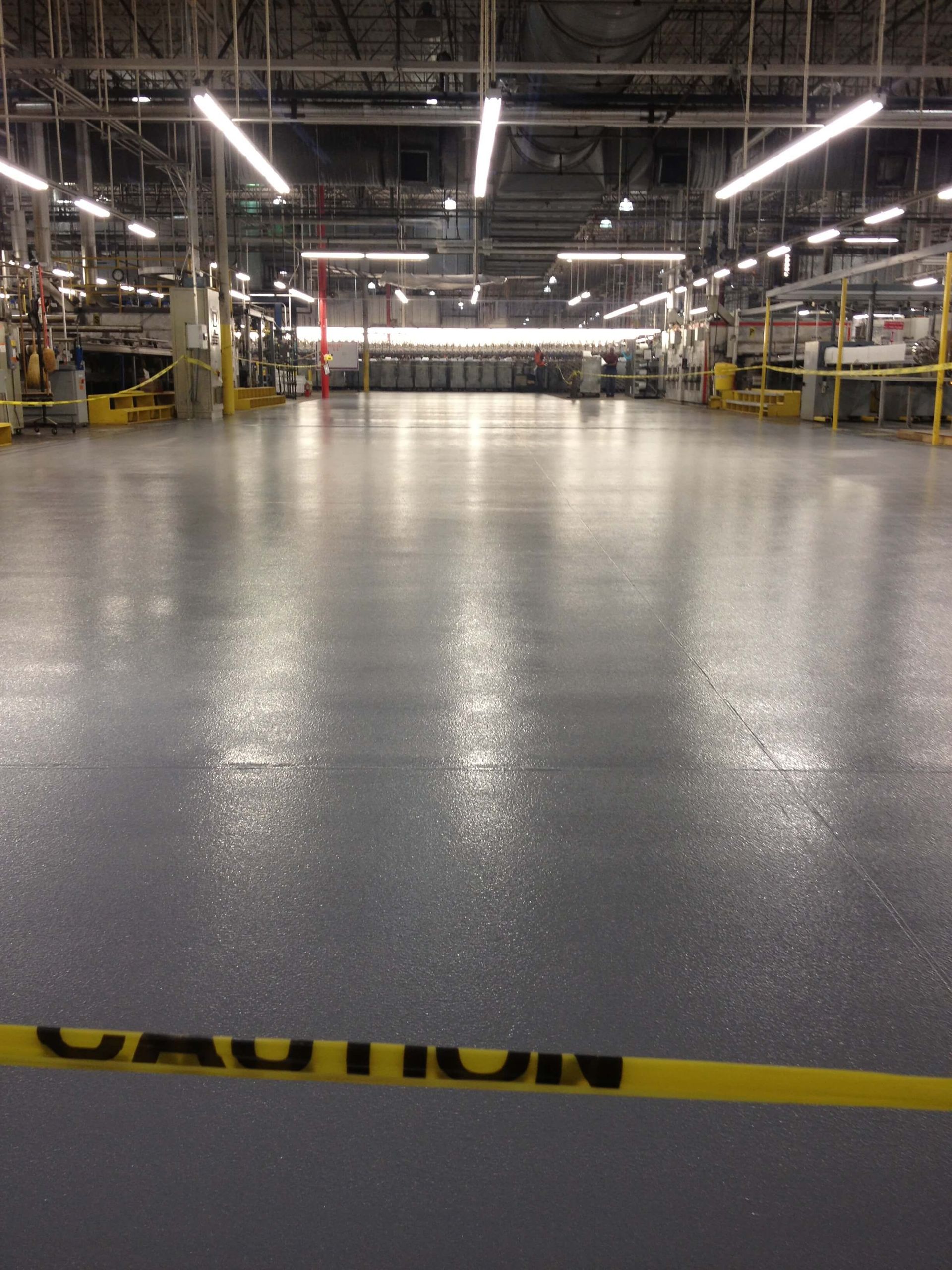 Grey industrial factory floor with caution tape.