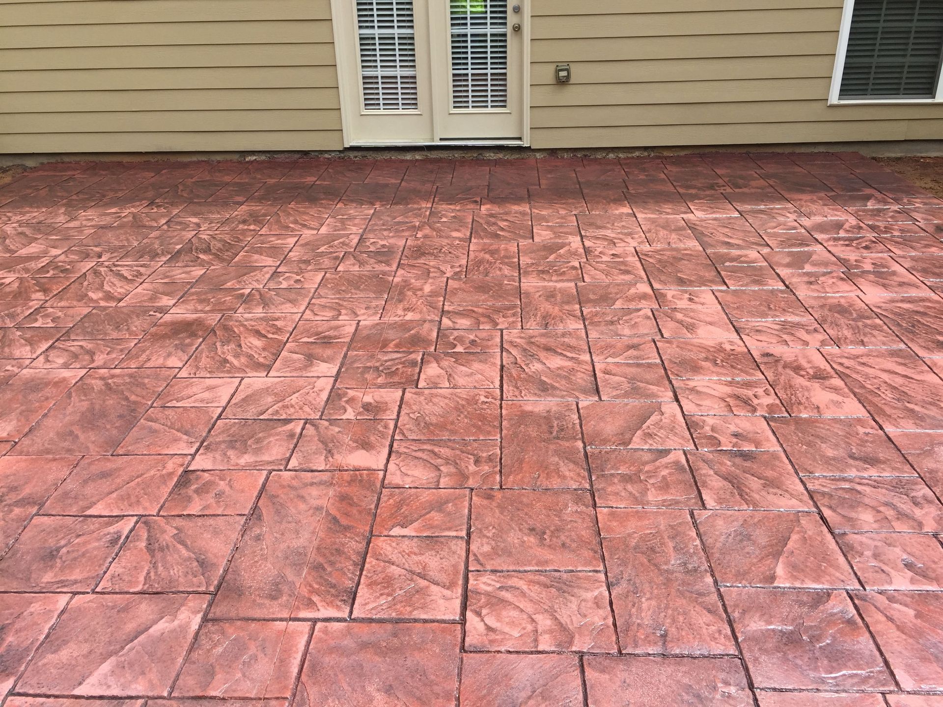 A red brick patio in front of a house with a door.