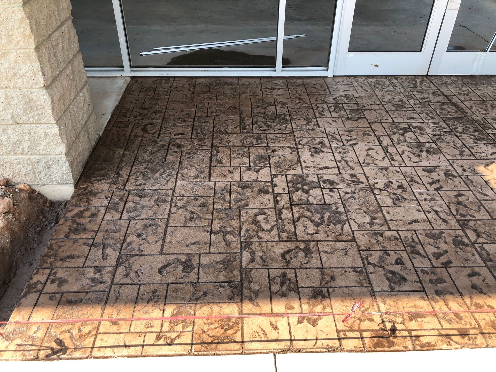 A concrete floor in front of a building with a sliding glass door.