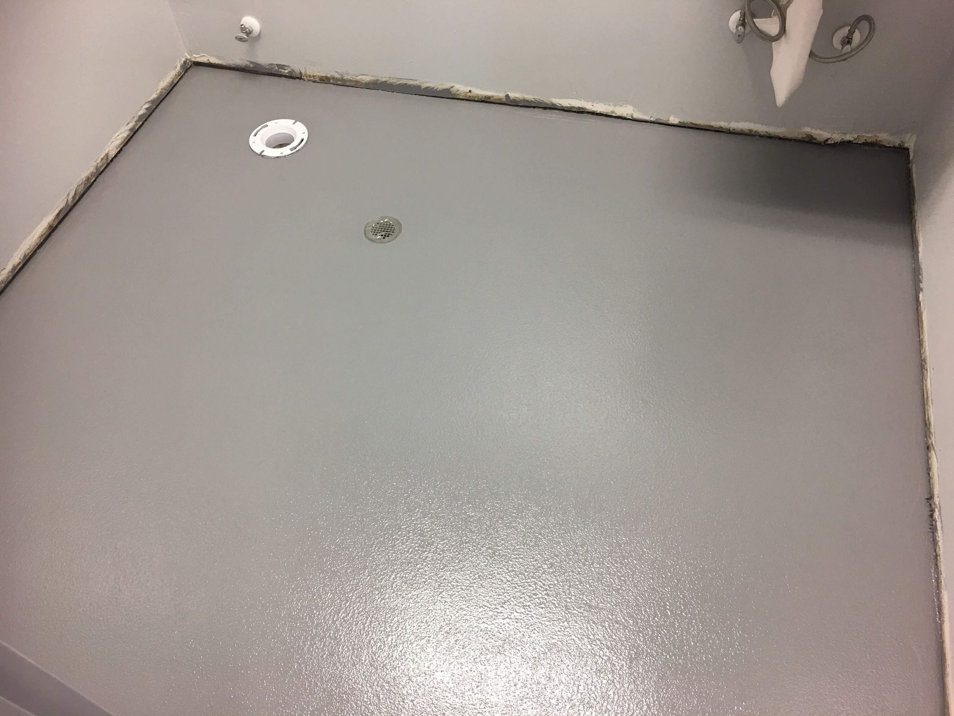 Gray painted wall with a light fixture, a recessed light, and a rough perimeter.