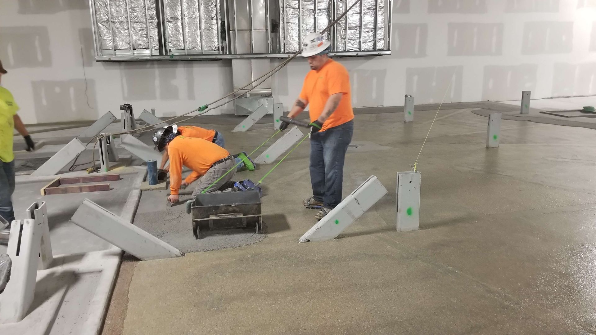 A group of construction workers are working on the floor of a building.