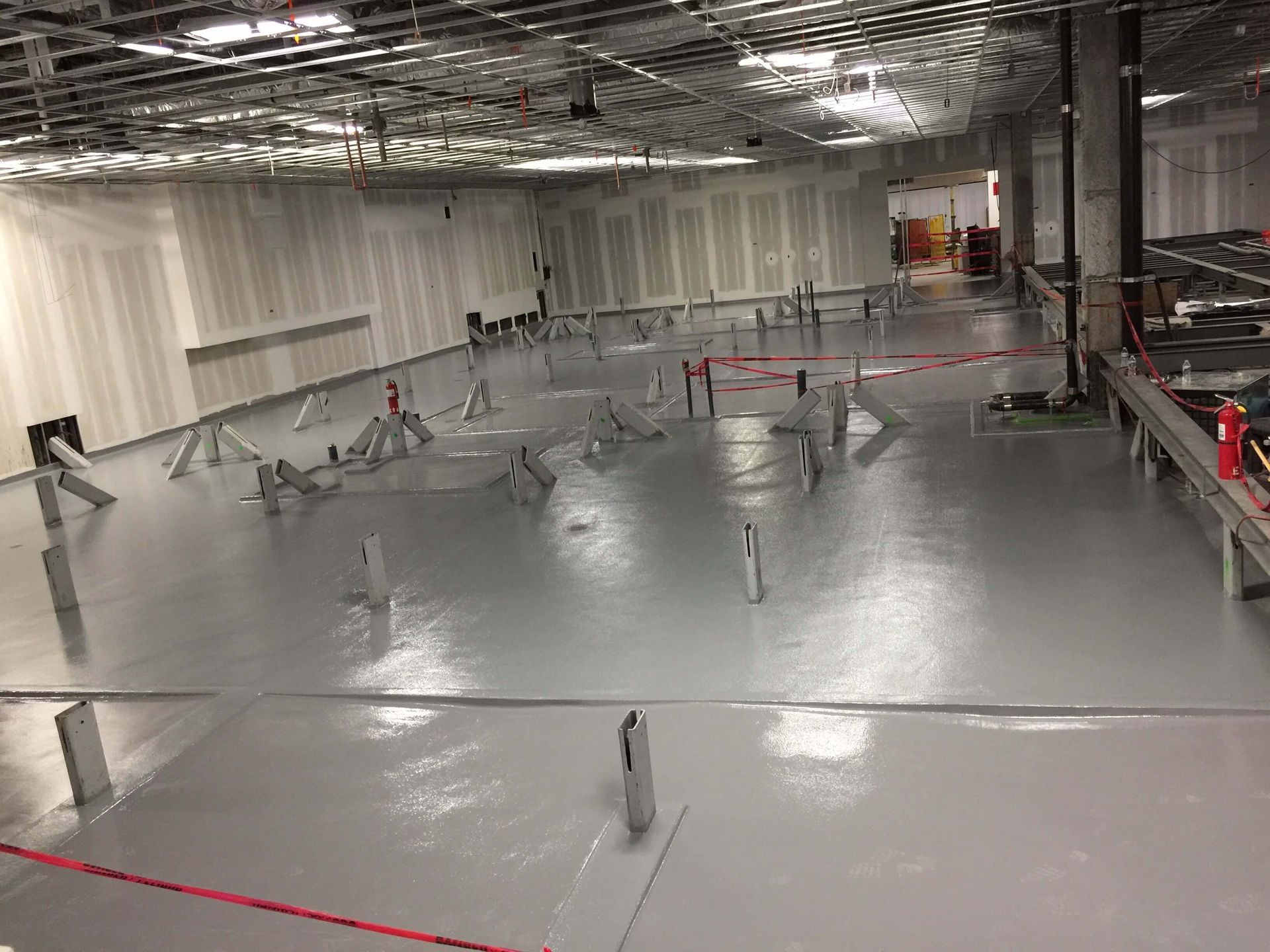 A large room with a gray floor and white walls is being remodeled.