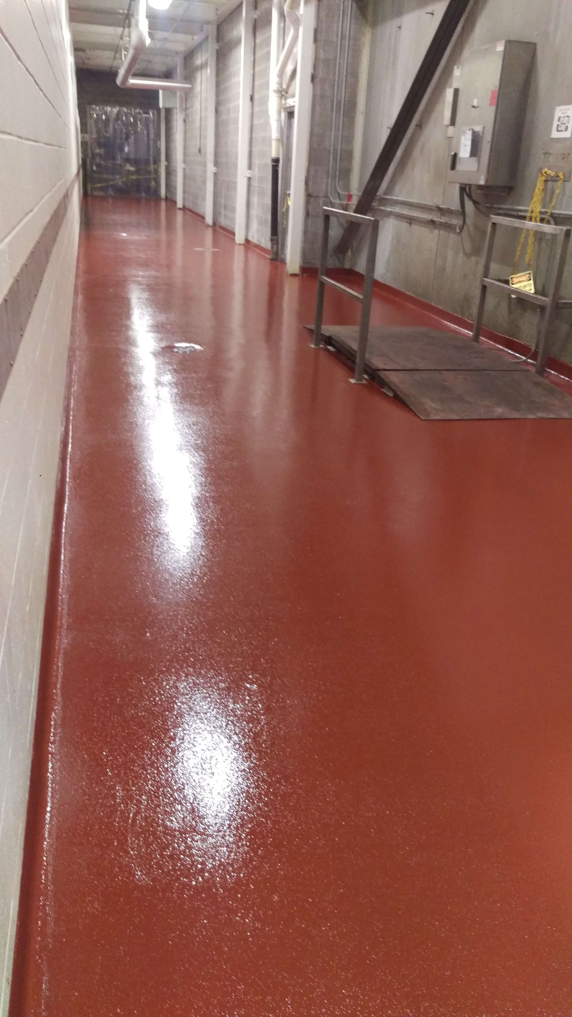 A long hallway with a red floor in a building.