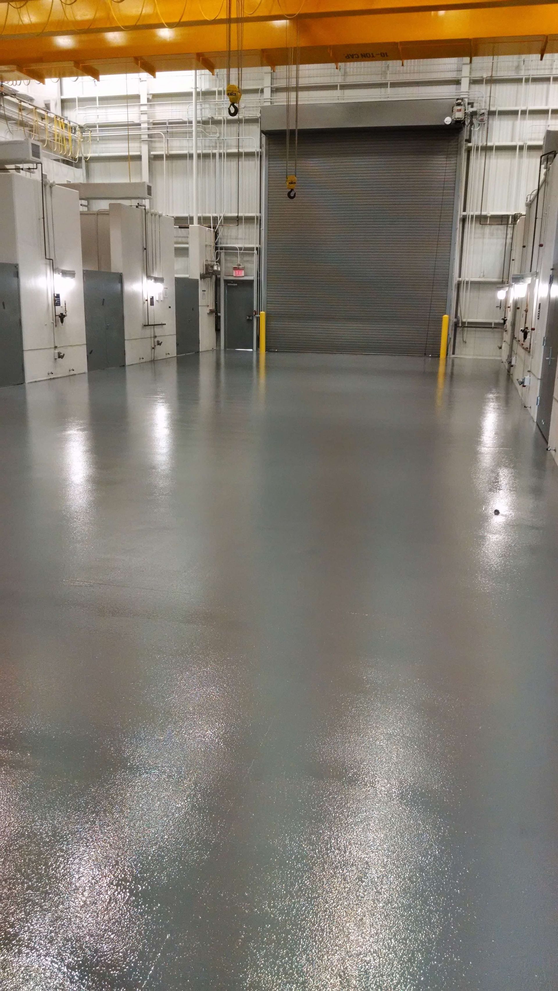 A large empty warehouse with a sliding door and a crane.