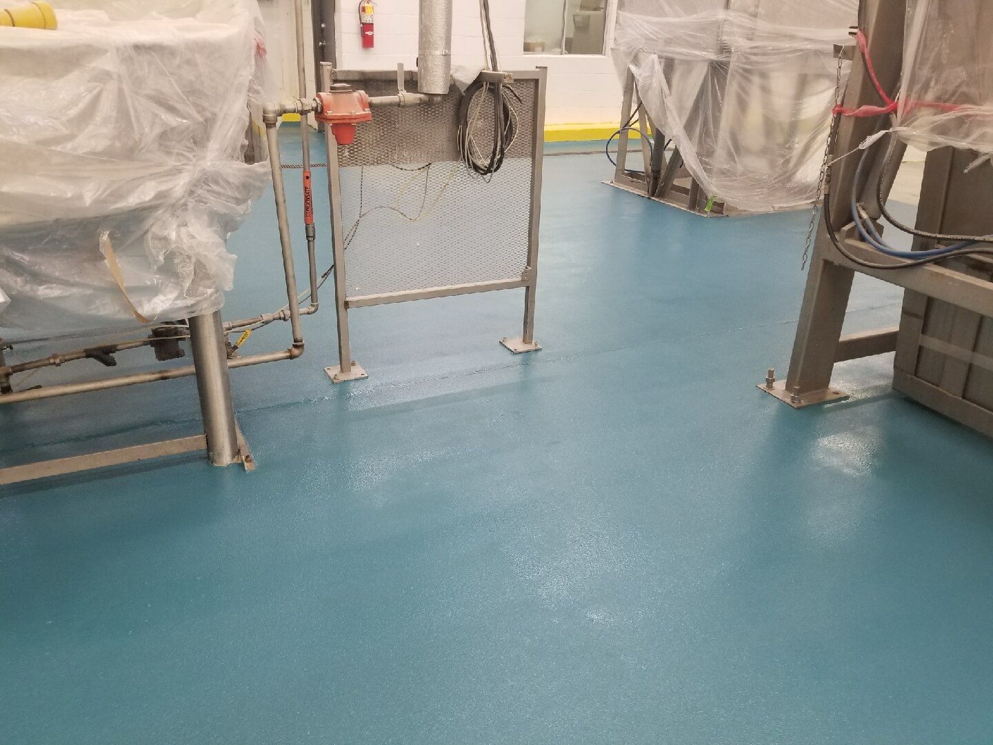 A blue floor in a factory with a lot of machinery.