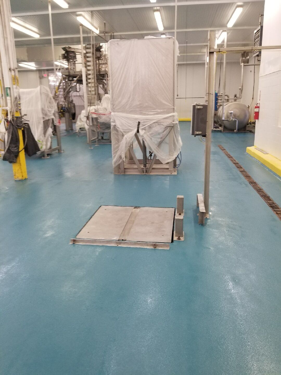 A warehouse with a blue floor and a stainless steel door.